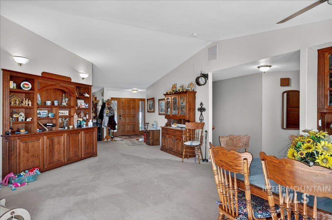 Dining room featuring light colored carpet, lofted ceiling, and ceiling fan