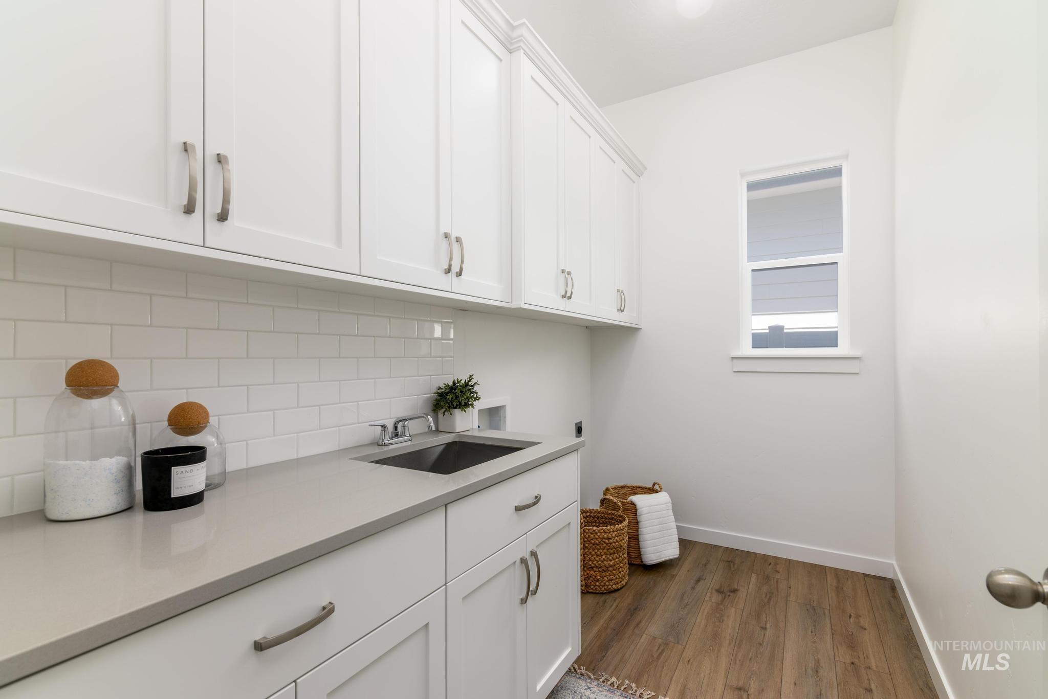 Washroom with dark wood-style floors and cabinet space