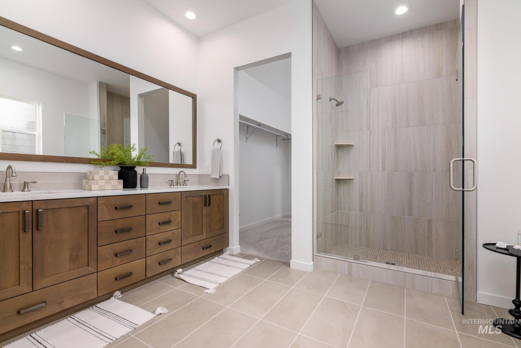 Bathroom featuring light tile patterned flooring, double vanity, a spacious closet, a stall shower, and recessed lighting