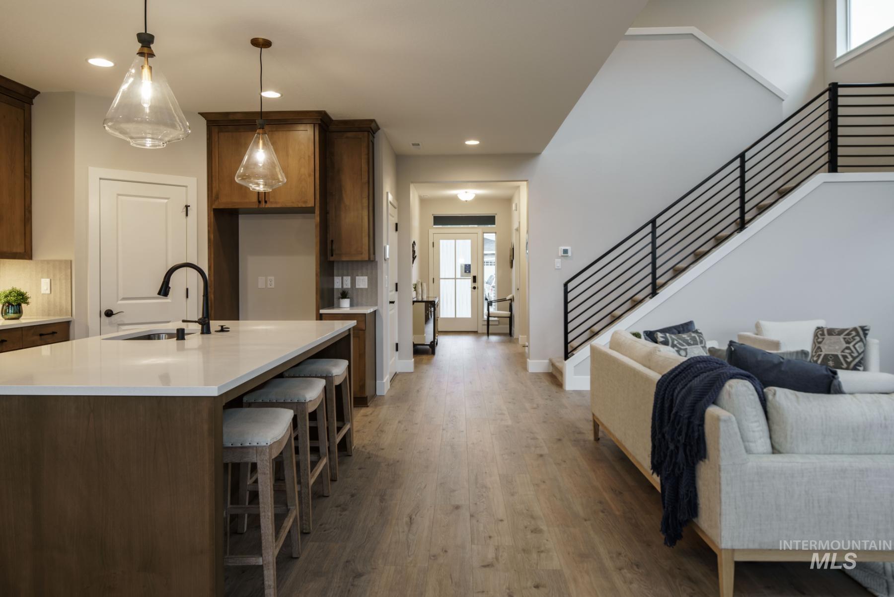 Kitchen with light wood-type flooring, light countertops, open floor plan, recessed lighting, and decorative light fixtures