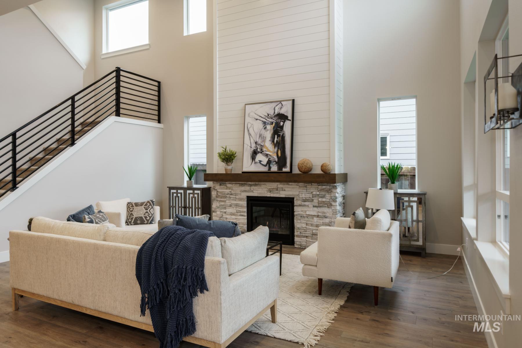 Living room with a towering ceiling, a stone fireplace, and dark wood-style flooring