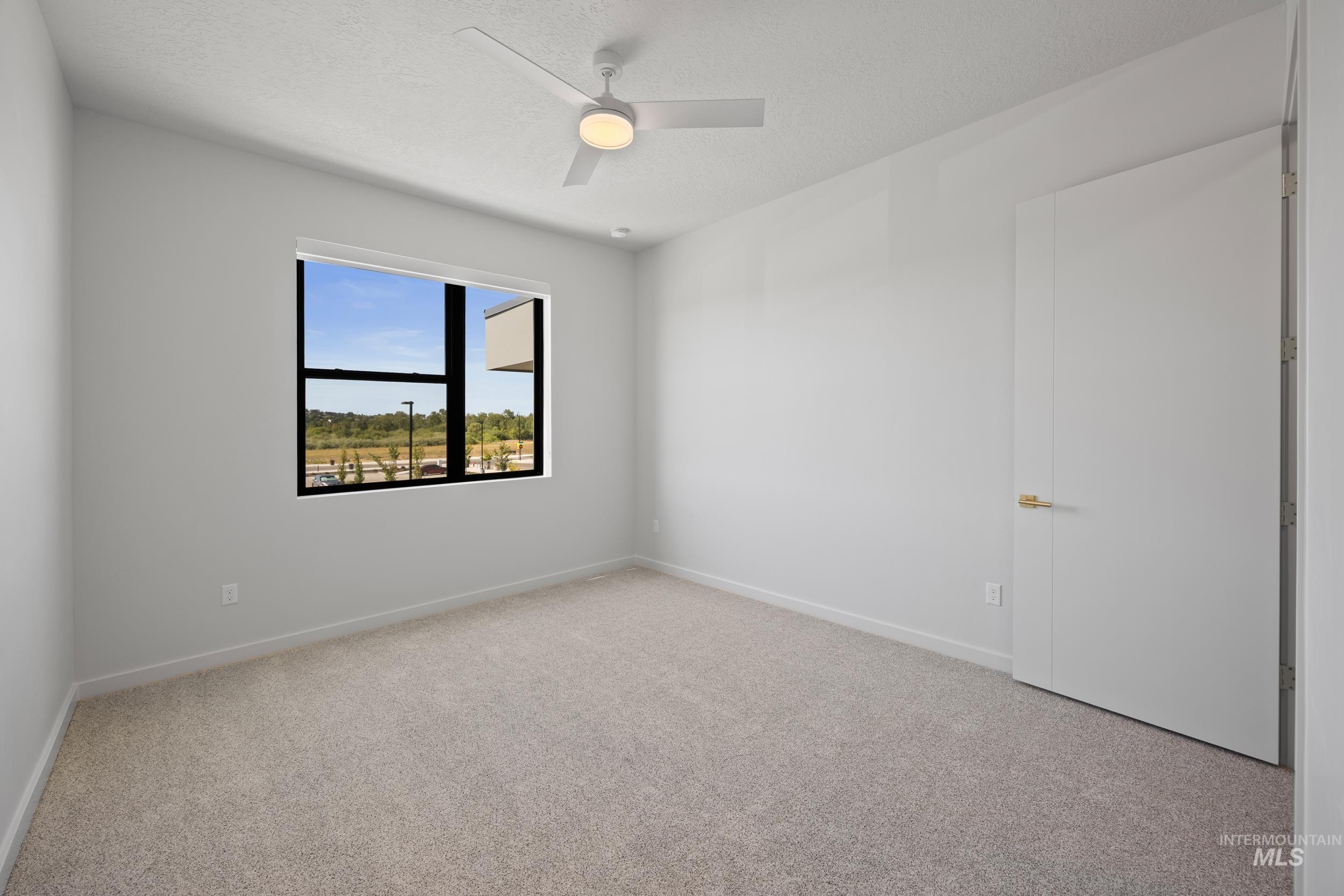 Carpeted empty room featuring a ceiling fan and a textured ceiling