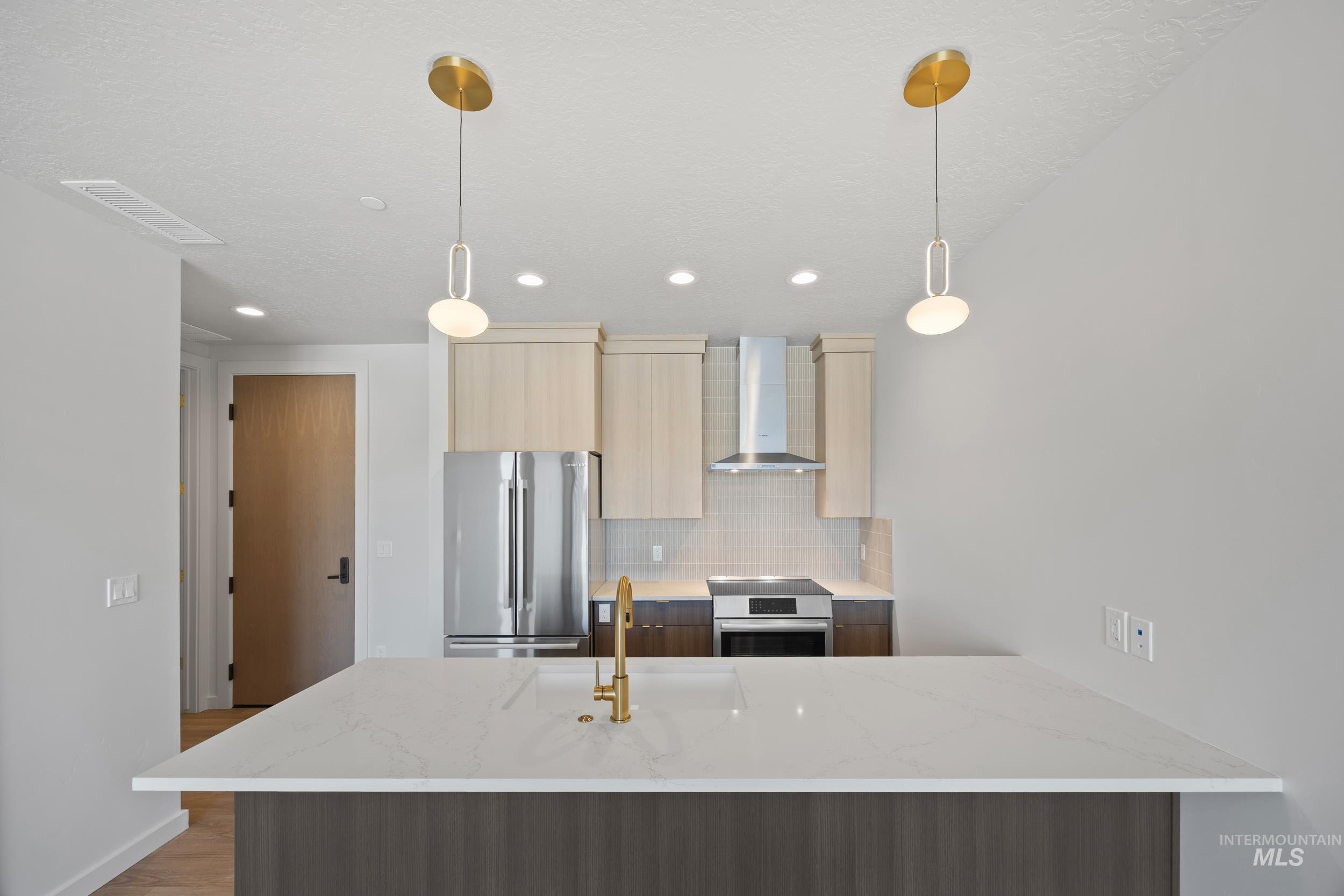 Kitchen featuring light stone countertops, modern cabinets, backsplash, stainless steel appliances, and wall chimney exhaust hood