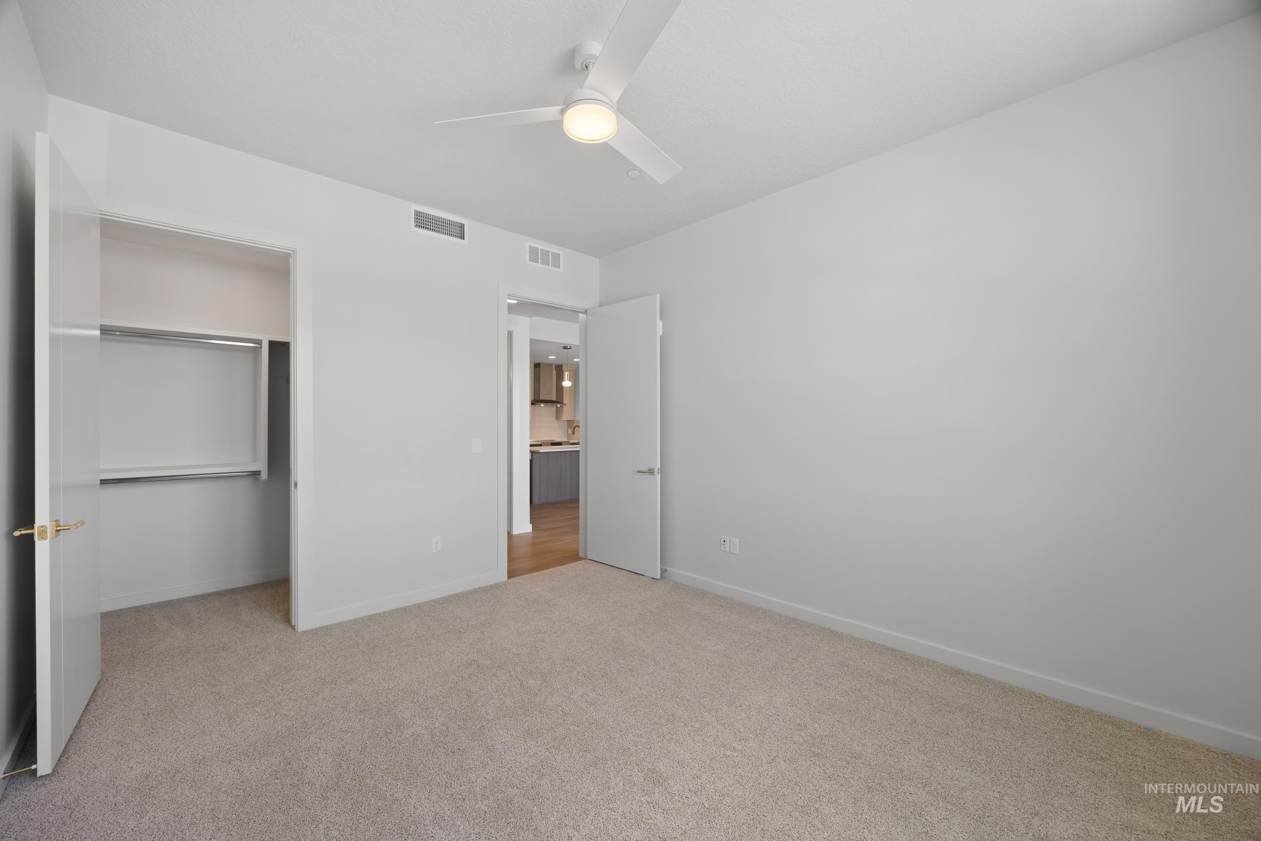 Unfurnished bedroom with light carpet, ceiling fan, and a closet
