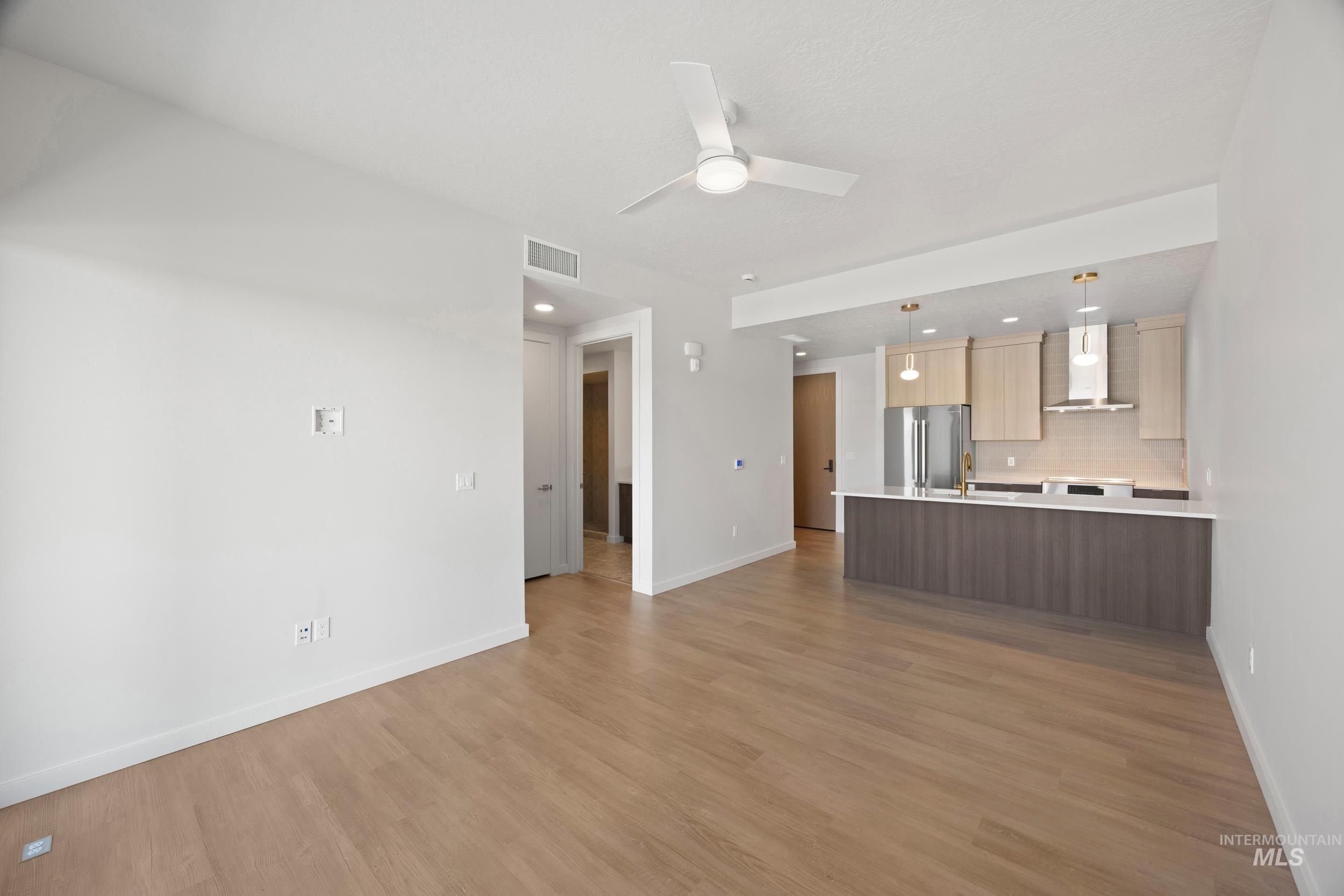 Unfurnished living room featuring light wood-style floors, a ceiling fan, and recessed lighting