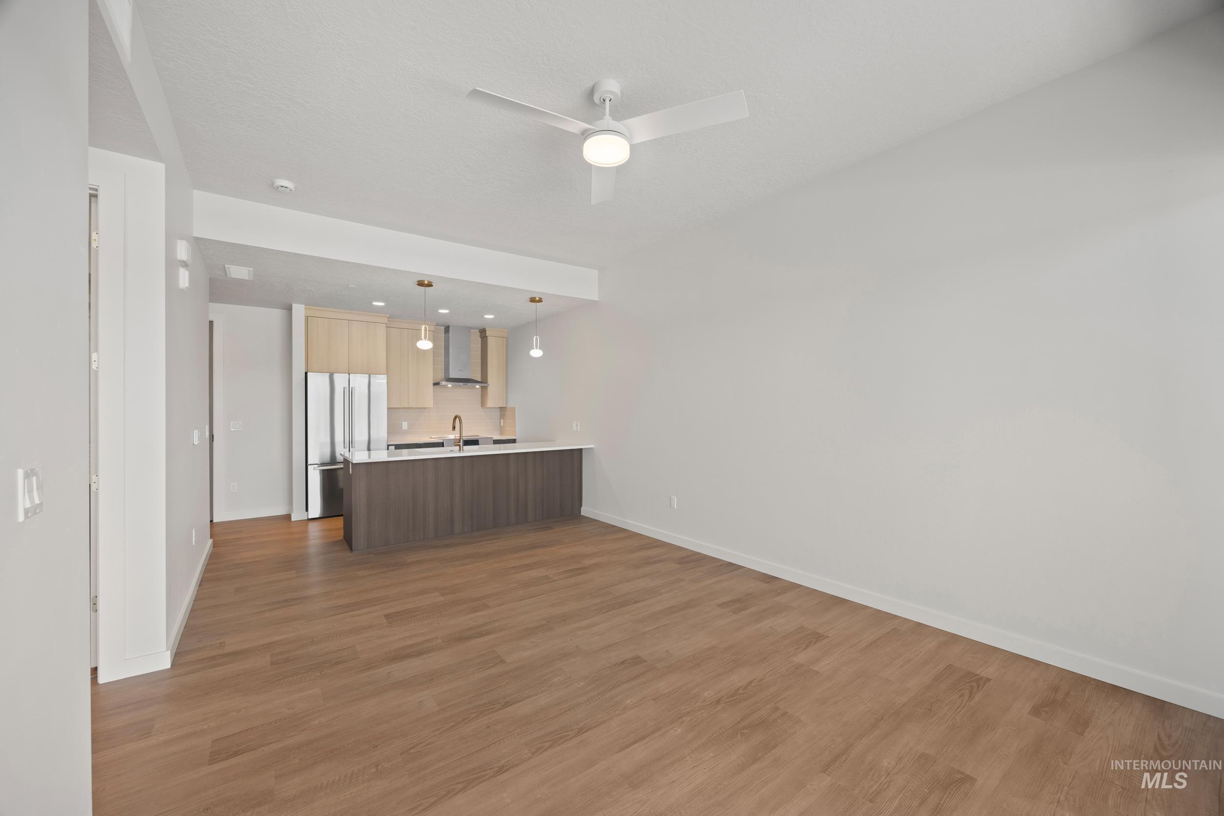 Unfurnished living room featuring dark wood-style floors and ceiling fan