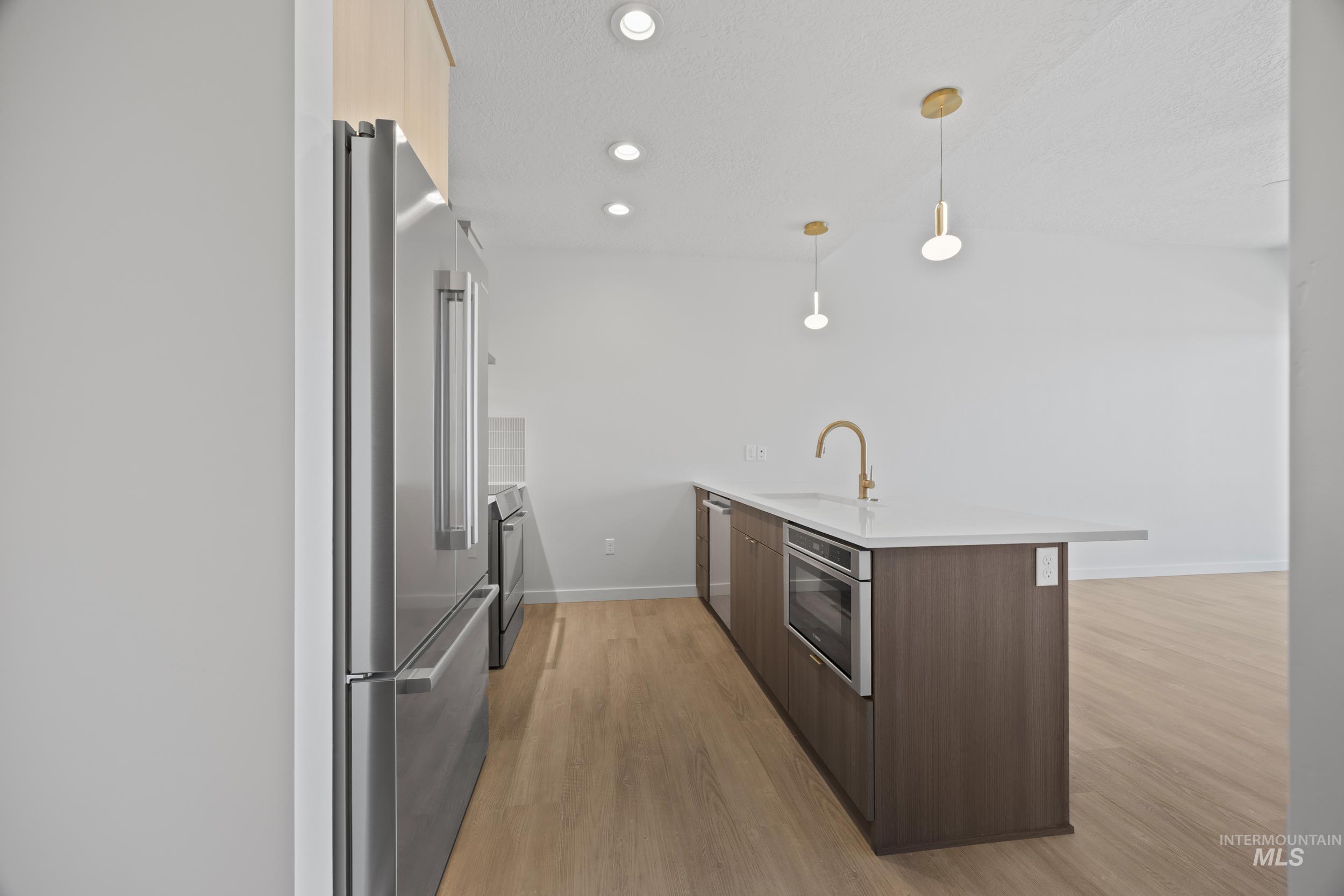 Kitchen featuring modern cabinets, appliances with stainless steel finishes, recessed lighting, light wood-style floors, and a peninsula