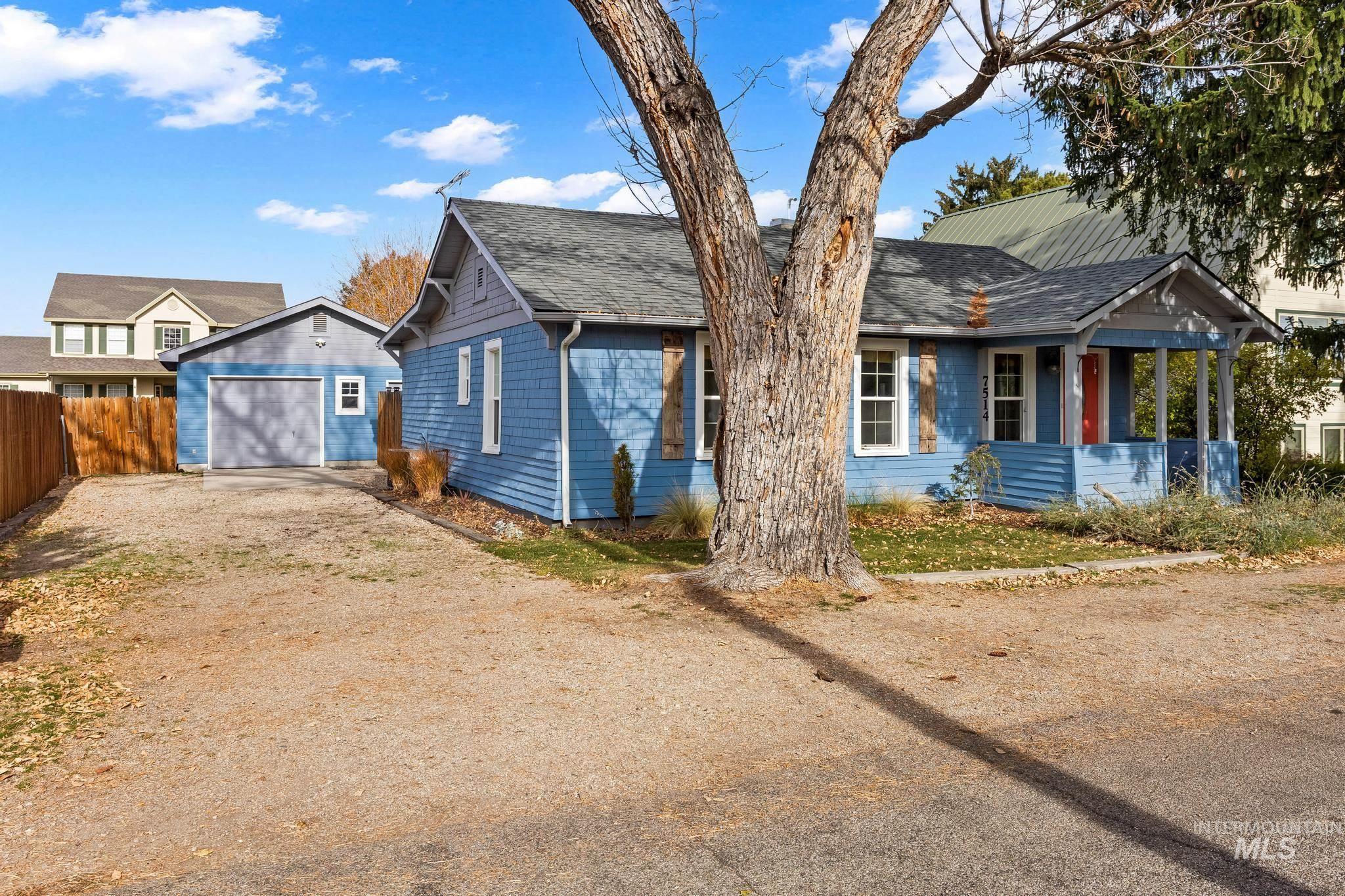 Ranch-style house with dirt driveway, an outbuilding, a shingled roof, covered porch, and a garage