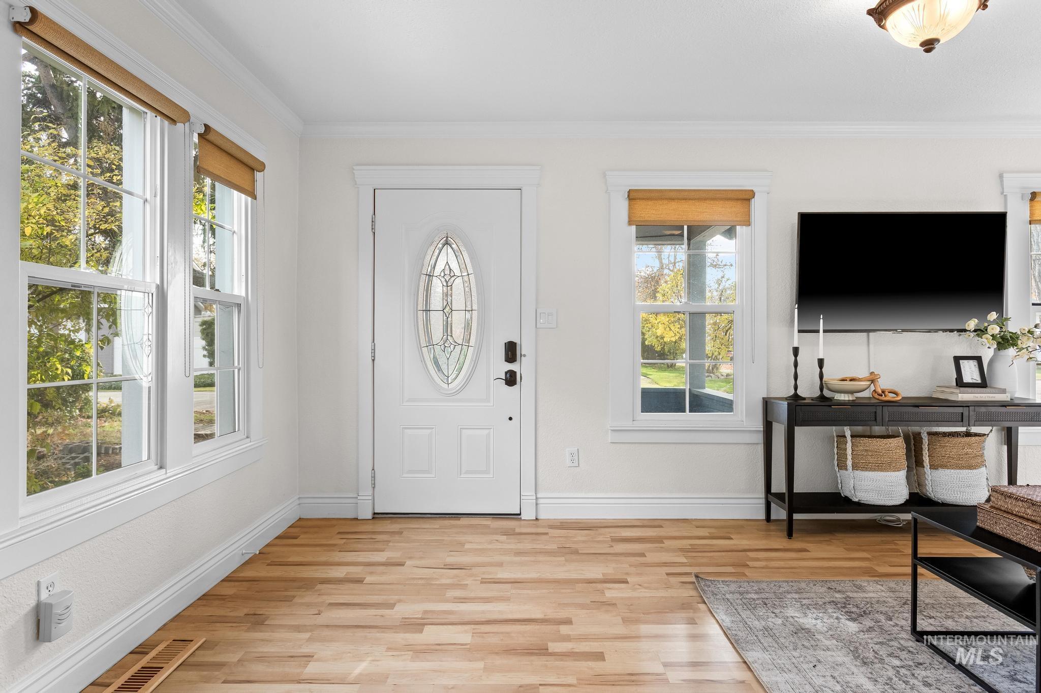 Foyer with light wood-type flooring and ornamental molding