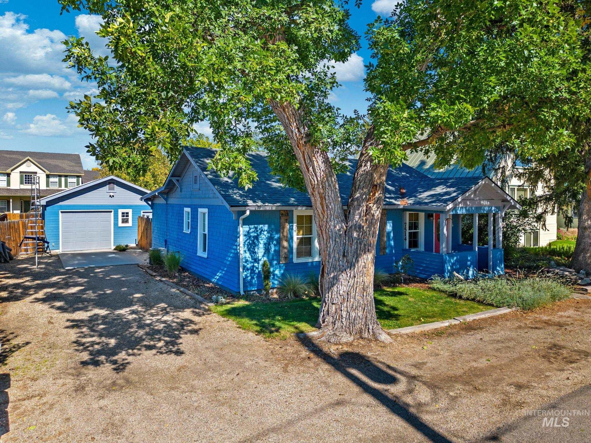 View of front of house featuring dirt driveway, an outdoor structure, a garage, a front lawn, and a porch