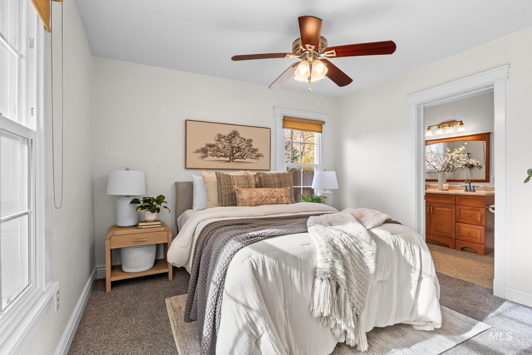 Bedroom with carpet floors, a ceiling fan, and ensuite bath