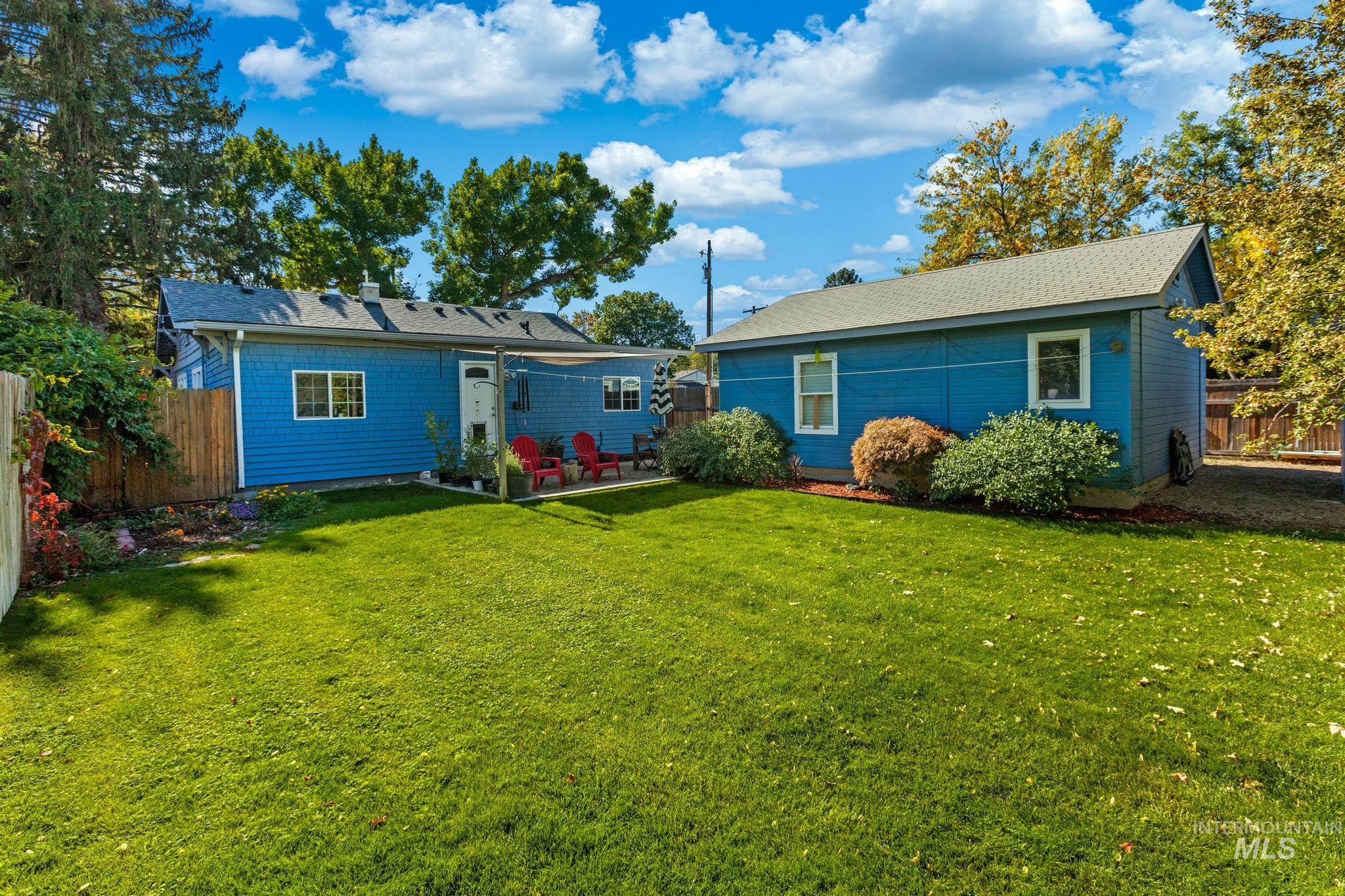 Back of house with a fenced backyard, a shingled roof, an outdoor structure, and a patio