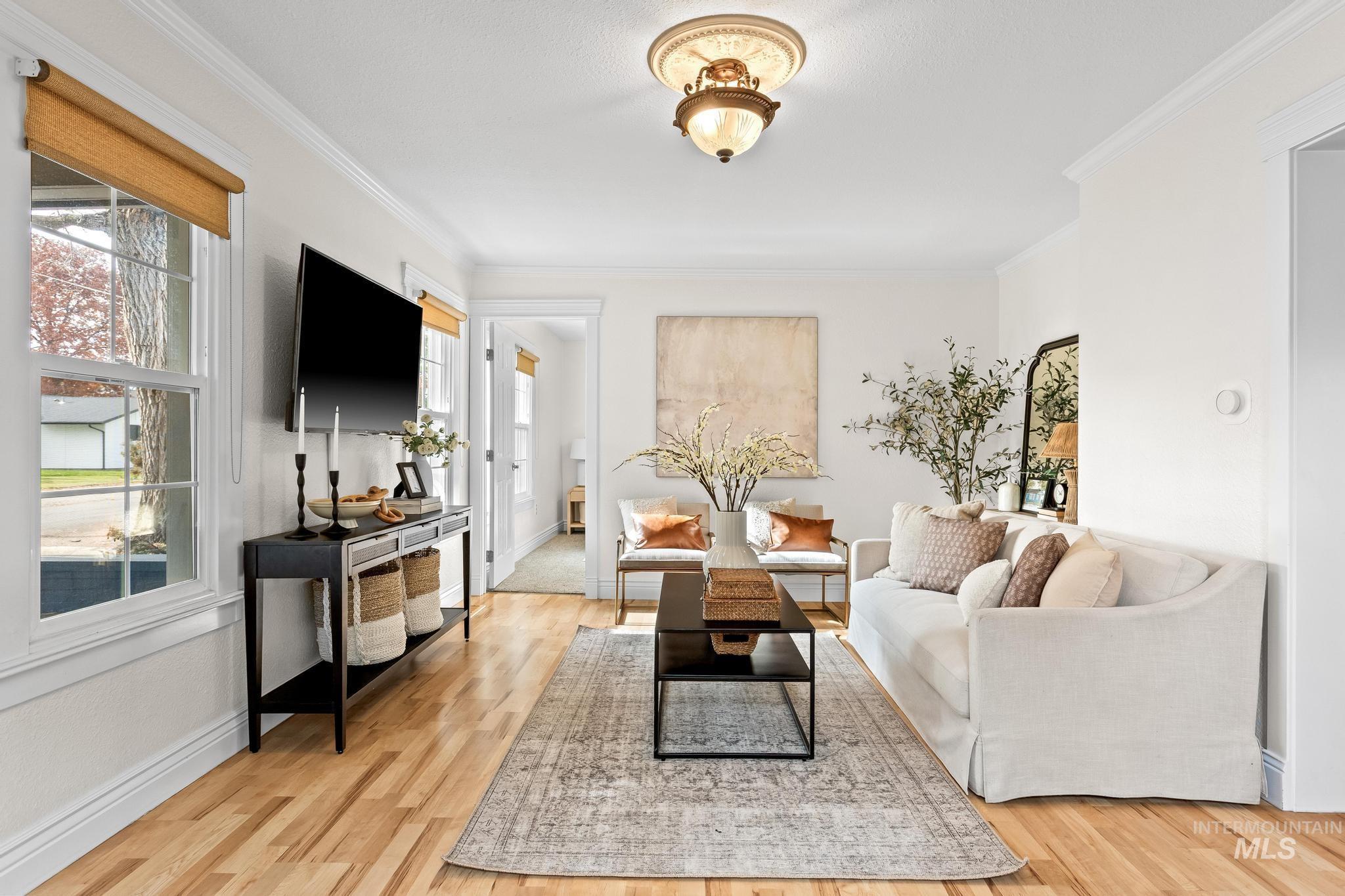 Living area featuring light wood finished floors, ornamental molding, and plenty of natural light