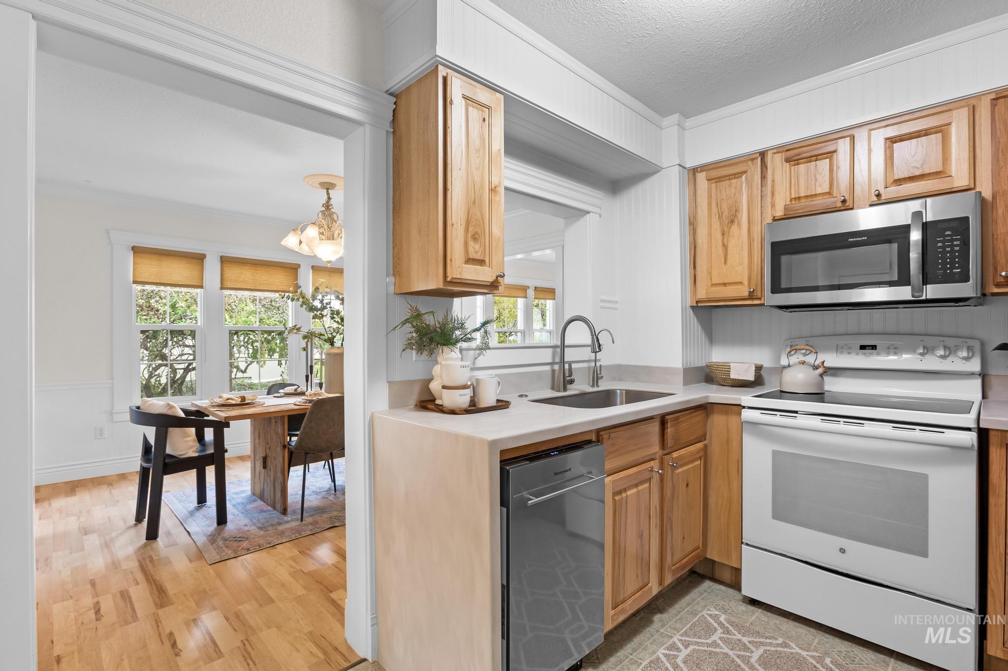 Kitchen with appliances with stainless steel finishes, light wood finished floors, a textured ceiling, and light stone countertops