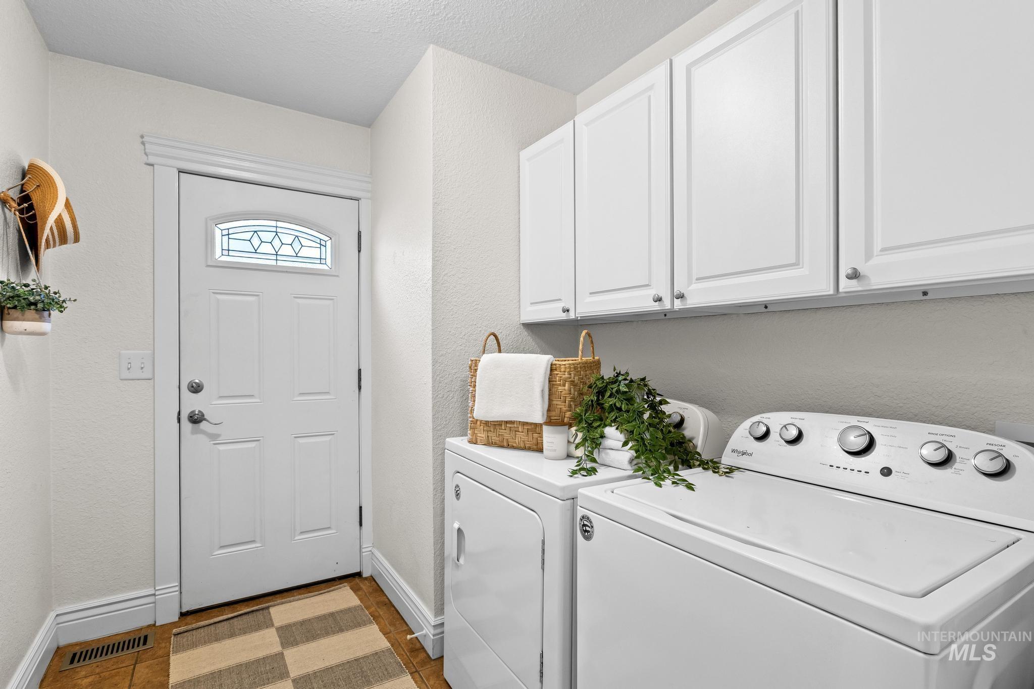 Laundry room with a textured wall, cabinet space, washer and dryer, and a textured ceiling