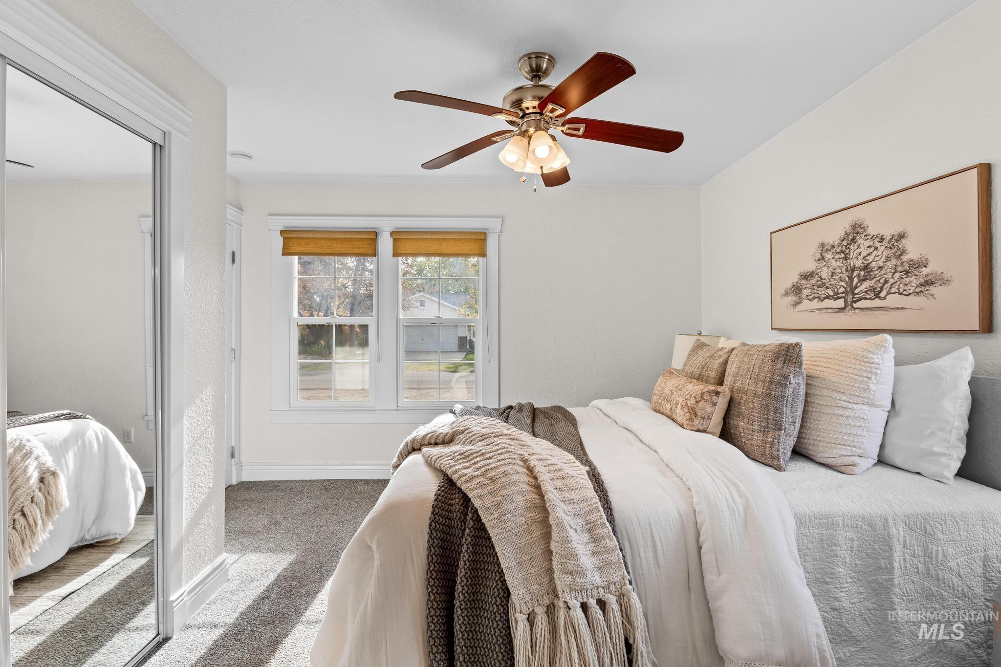 Carpeted bedroom with ceiling fan and a closet