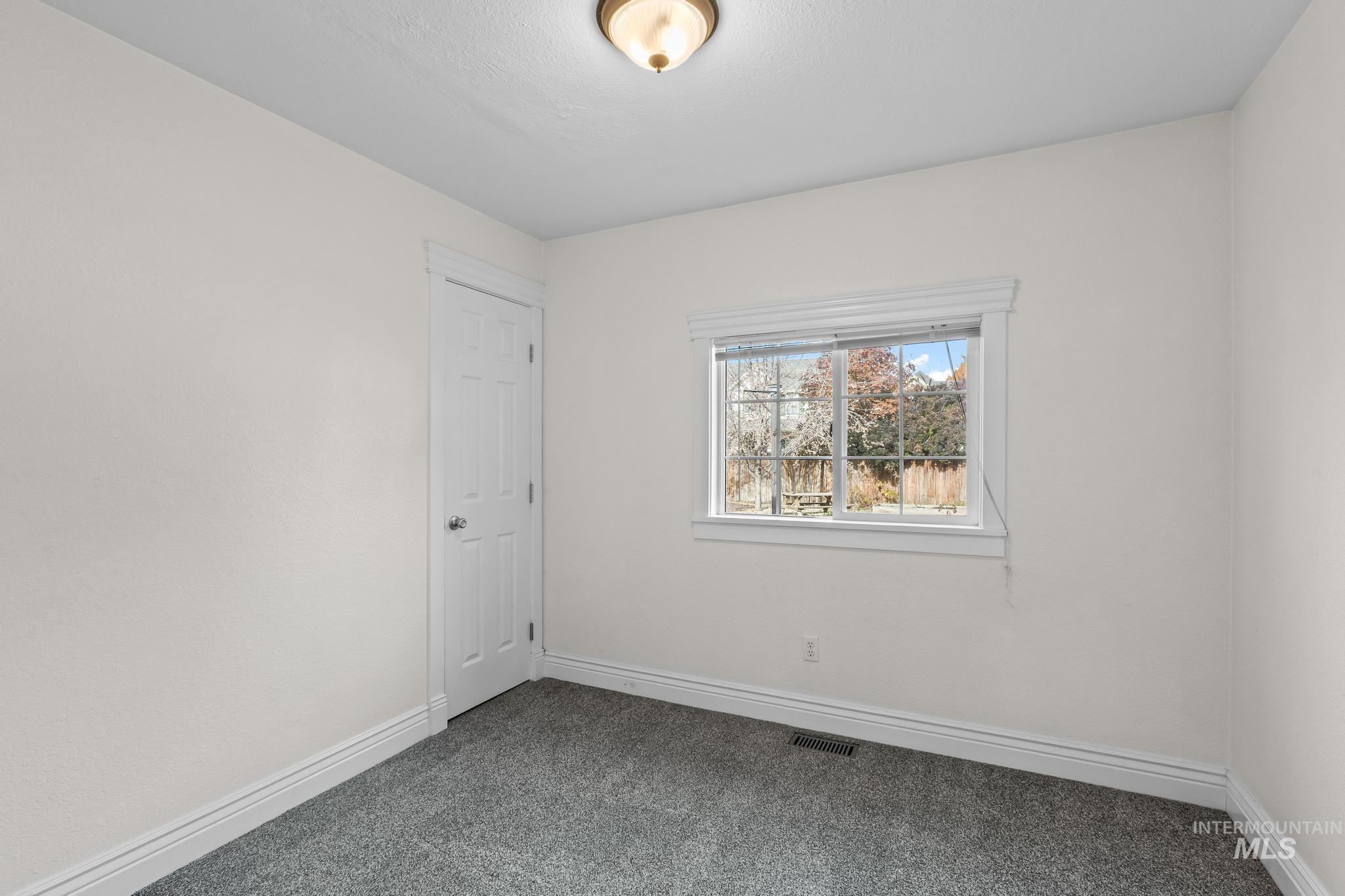 Carpeted spare room featuring baseboards