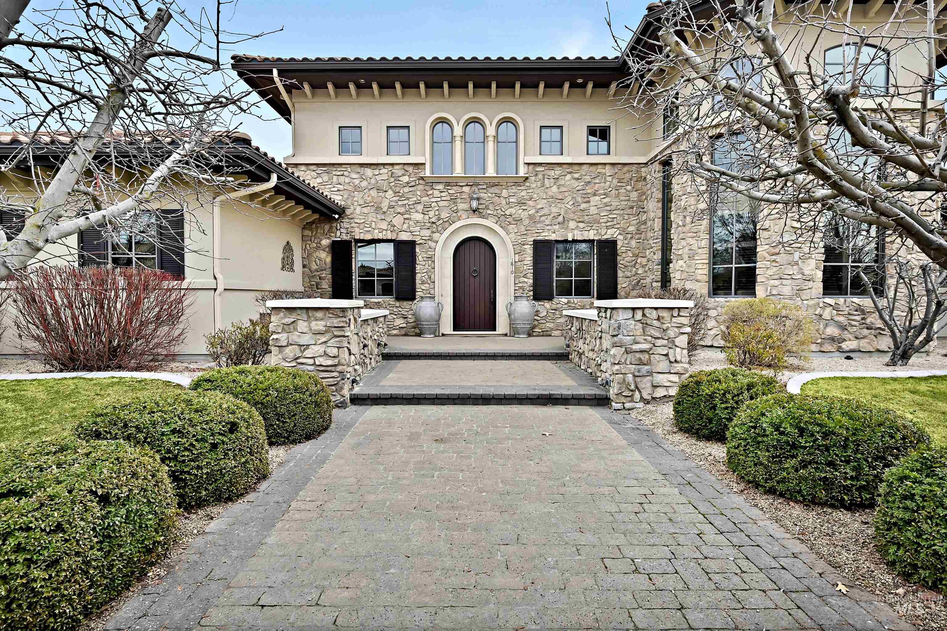 Mediterranean / spanish house featuring a tiled roof, stucco siding, and stone siding
