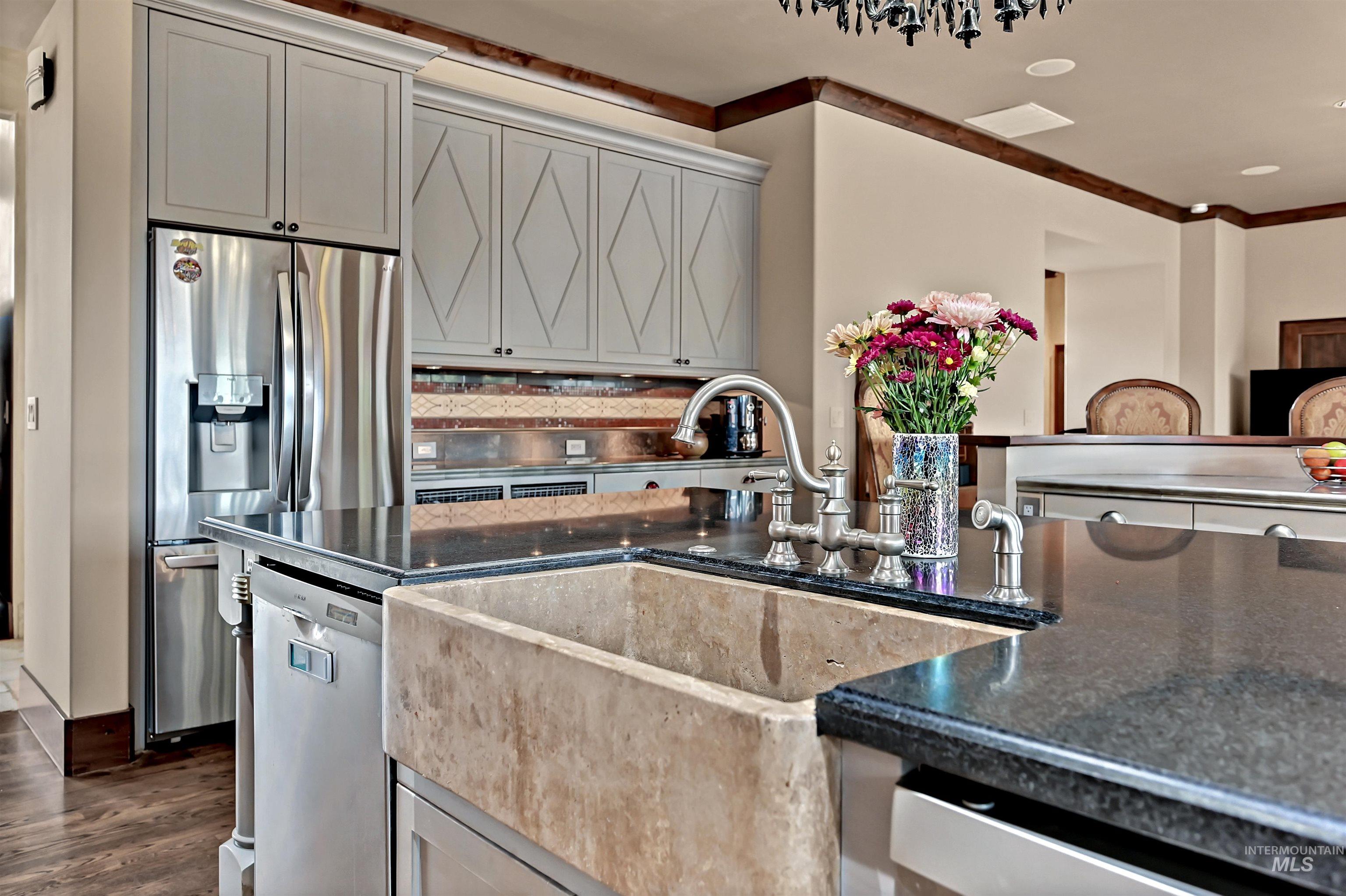 Kitchen featuring stainless steel appliances, dark stone counters, gray cabinetry, and dark wood finished floors