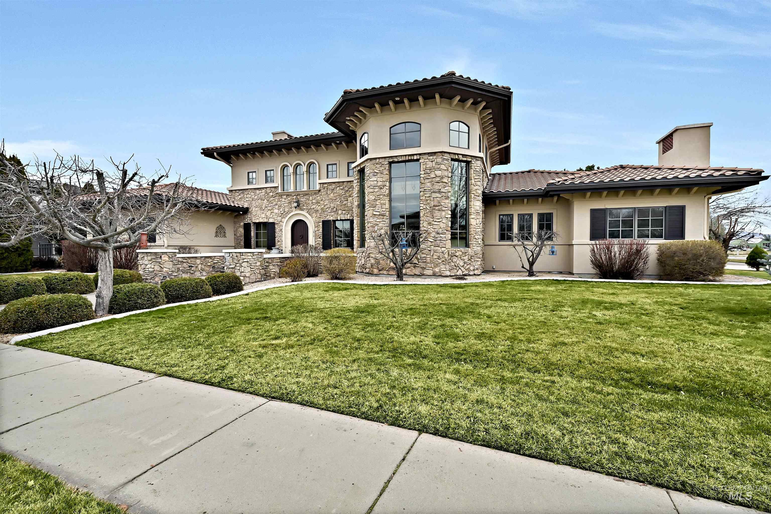 Mediterranean / italian-style home featuring stucco siding, a chimney, a front lawn, and stone siding