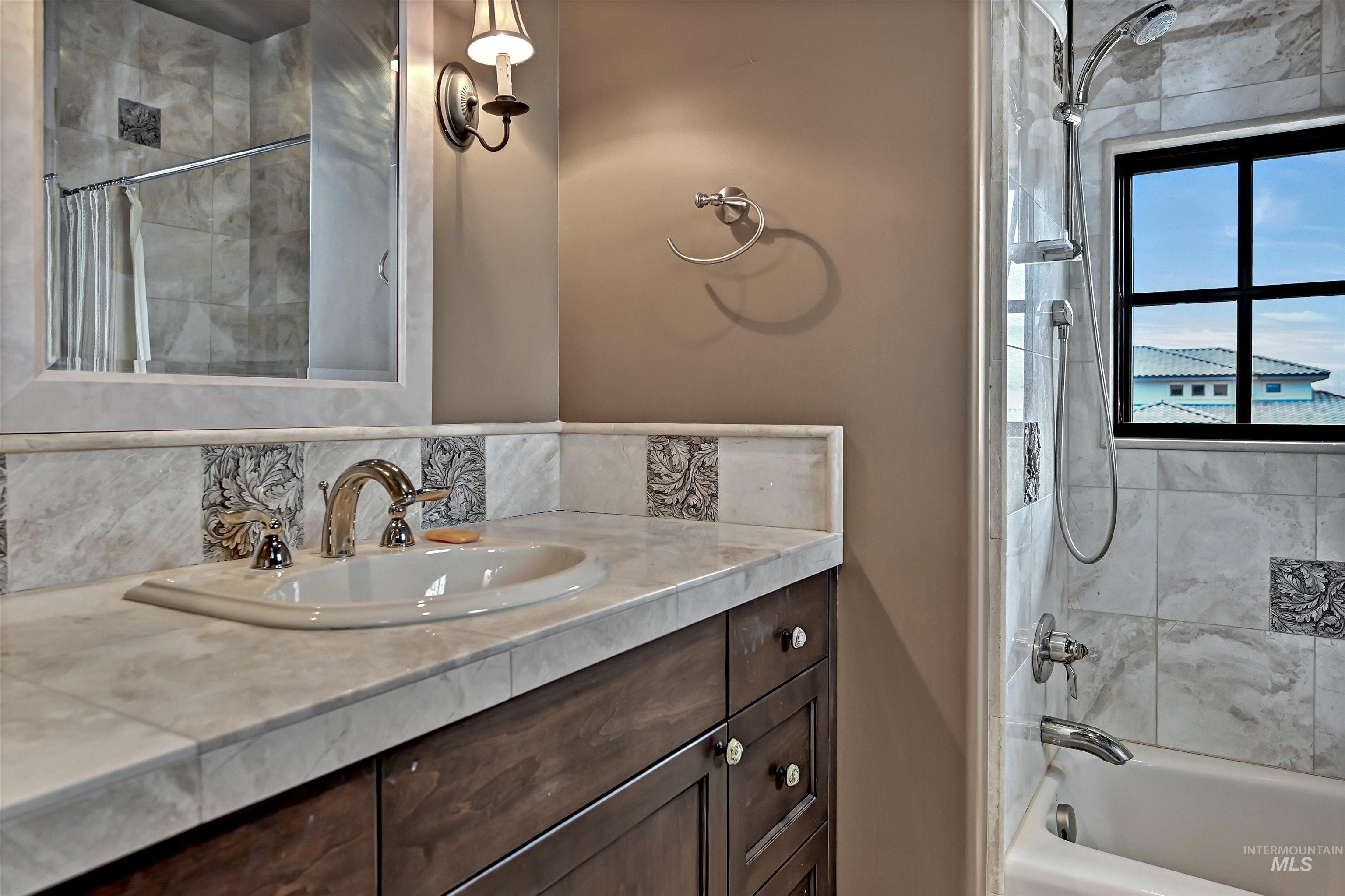 Bathroom featuring vanity, shower / bath combo with and decorative backsplash