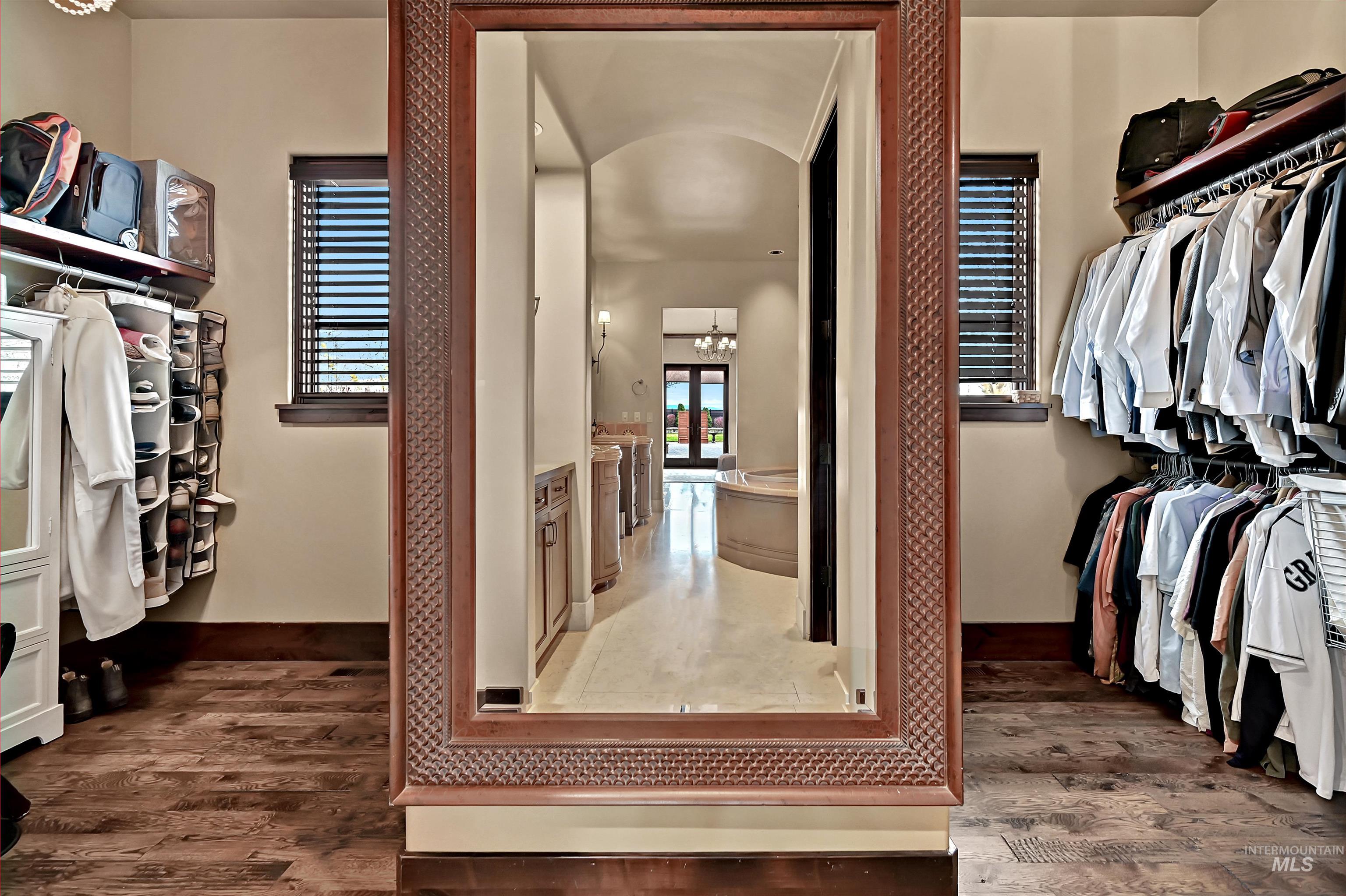 Walk in closet with arched walkways, dark wood-style flooring