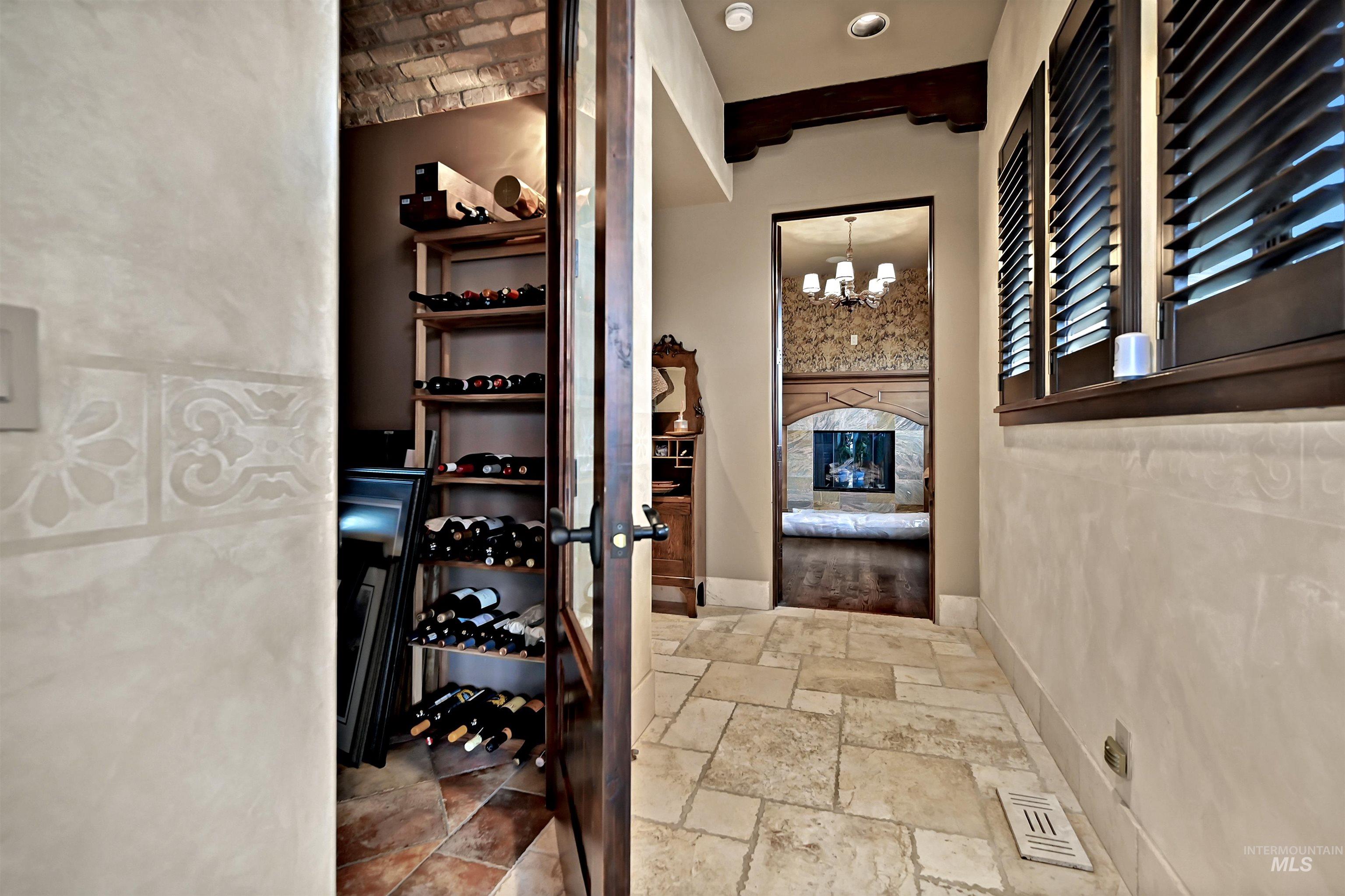 Wine room featuring a chandelier, stone tile floors, and beam ceiling