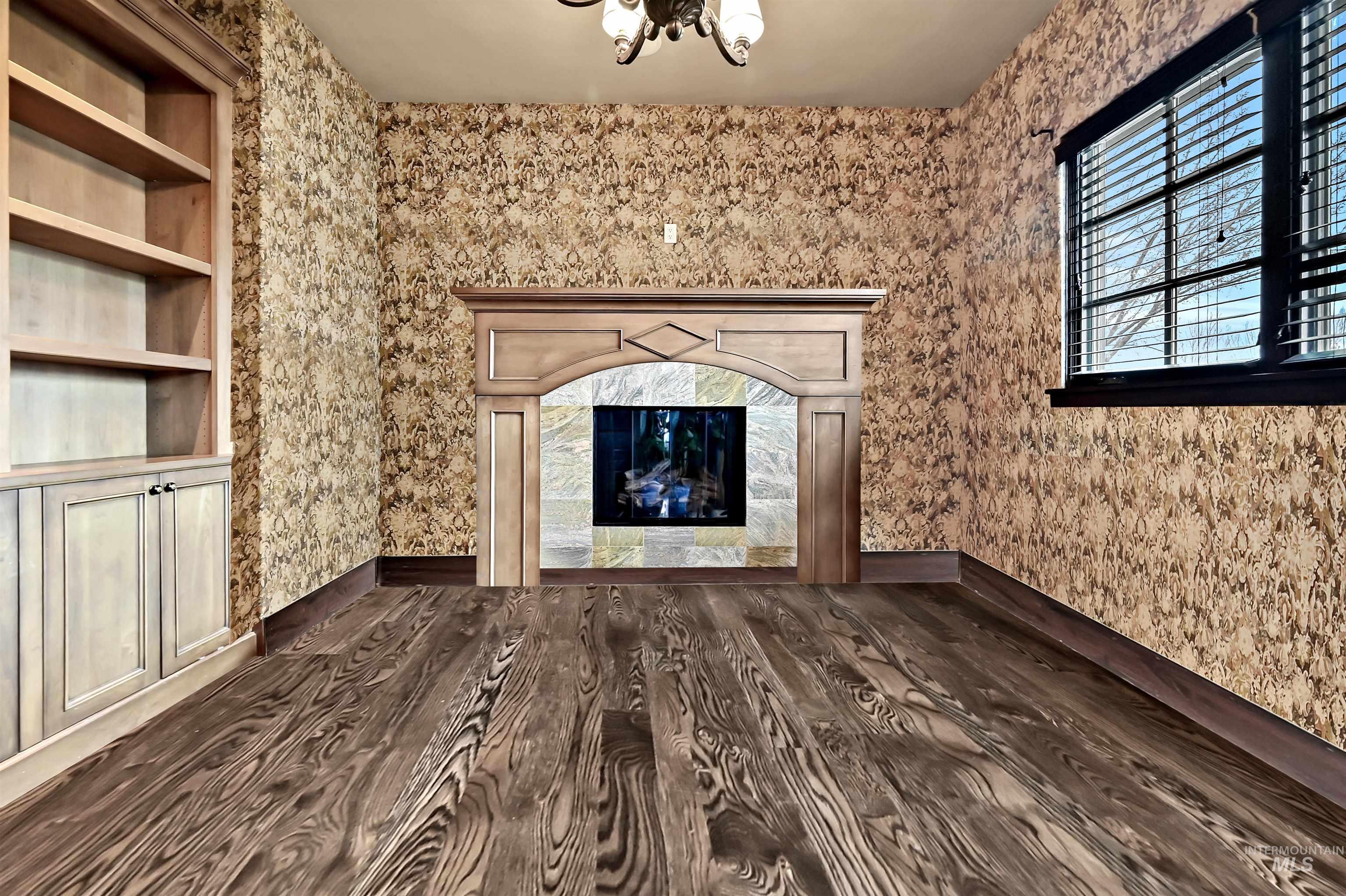 Library room with a high end fireplace and dark wood-style floors