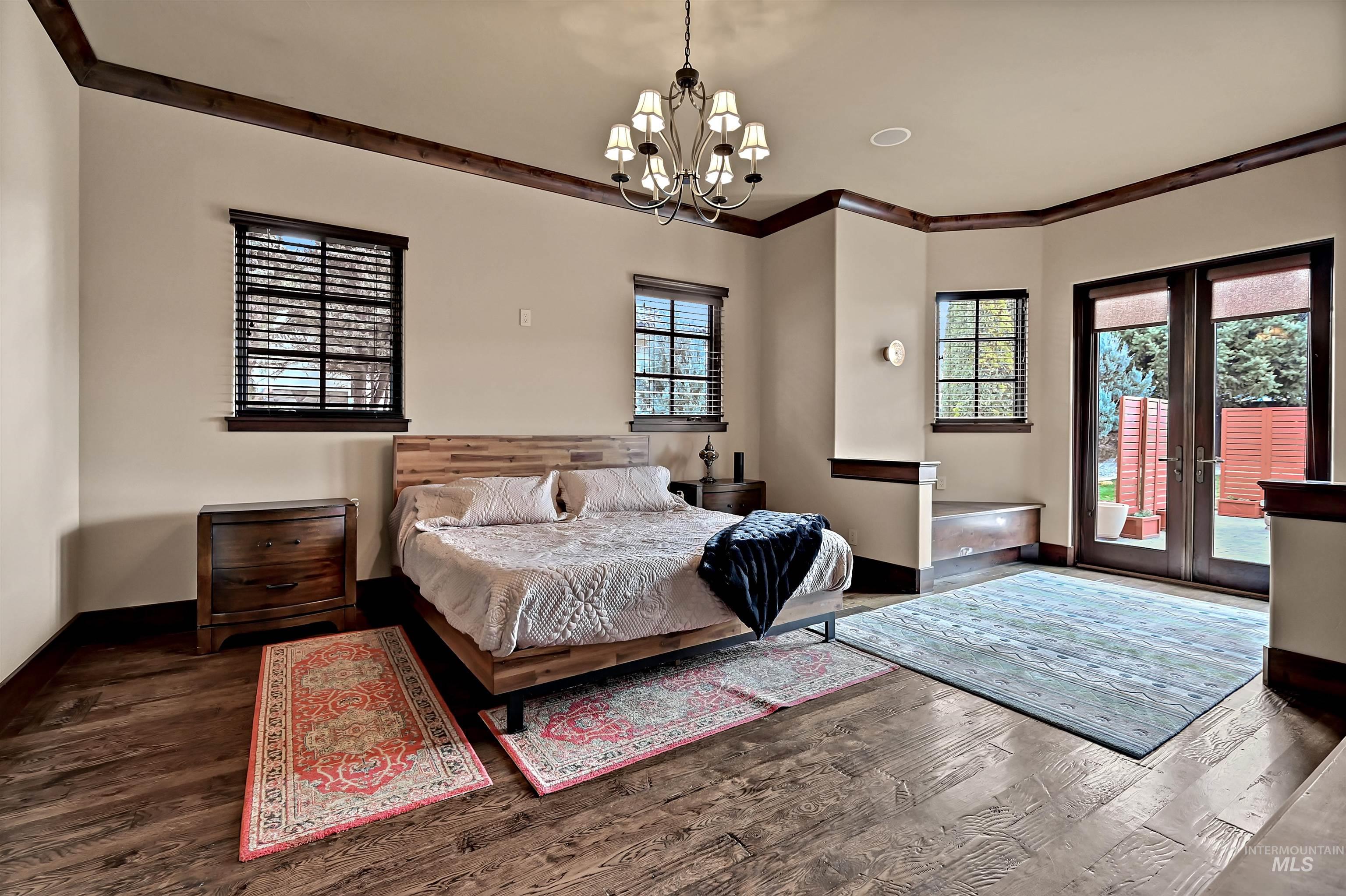 Bedroom featuring french doors, access to outside, hanging lights, dark wood-style floors, and crown molding