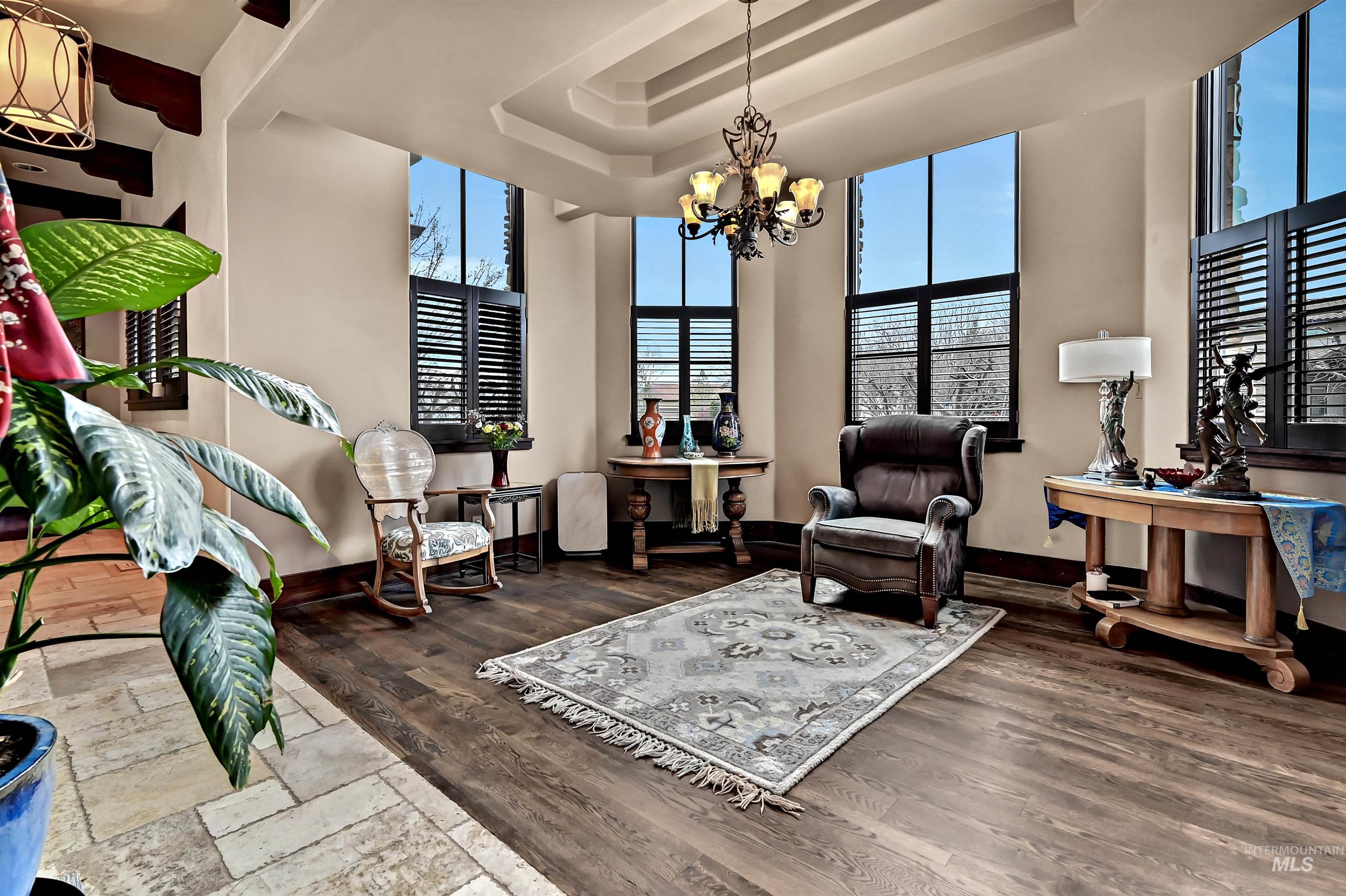 Living area featuring dark wood-style floors, a chandelier, and a high tray ceiling