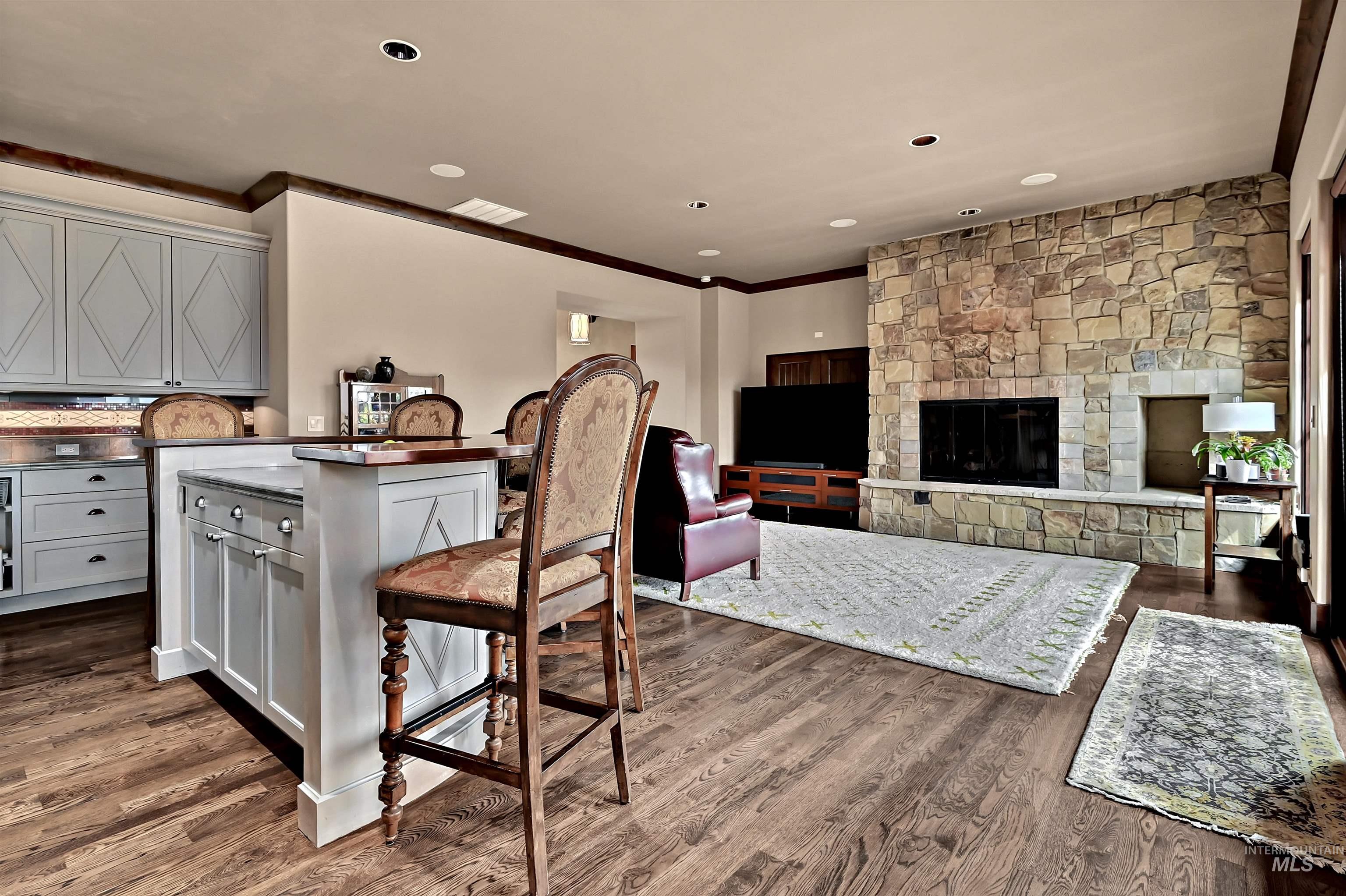 Kitchen featuring a breakfast bar, gray cabinets, open floor plan, a kitchen island, and crown molding