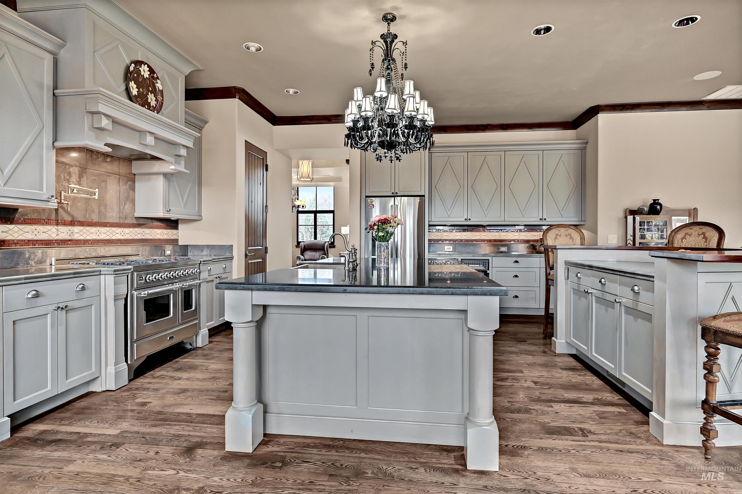 Kitchen featuring gray cabinetry, a kitchen bar, stainless steel appliances, crown molding, and chandelier