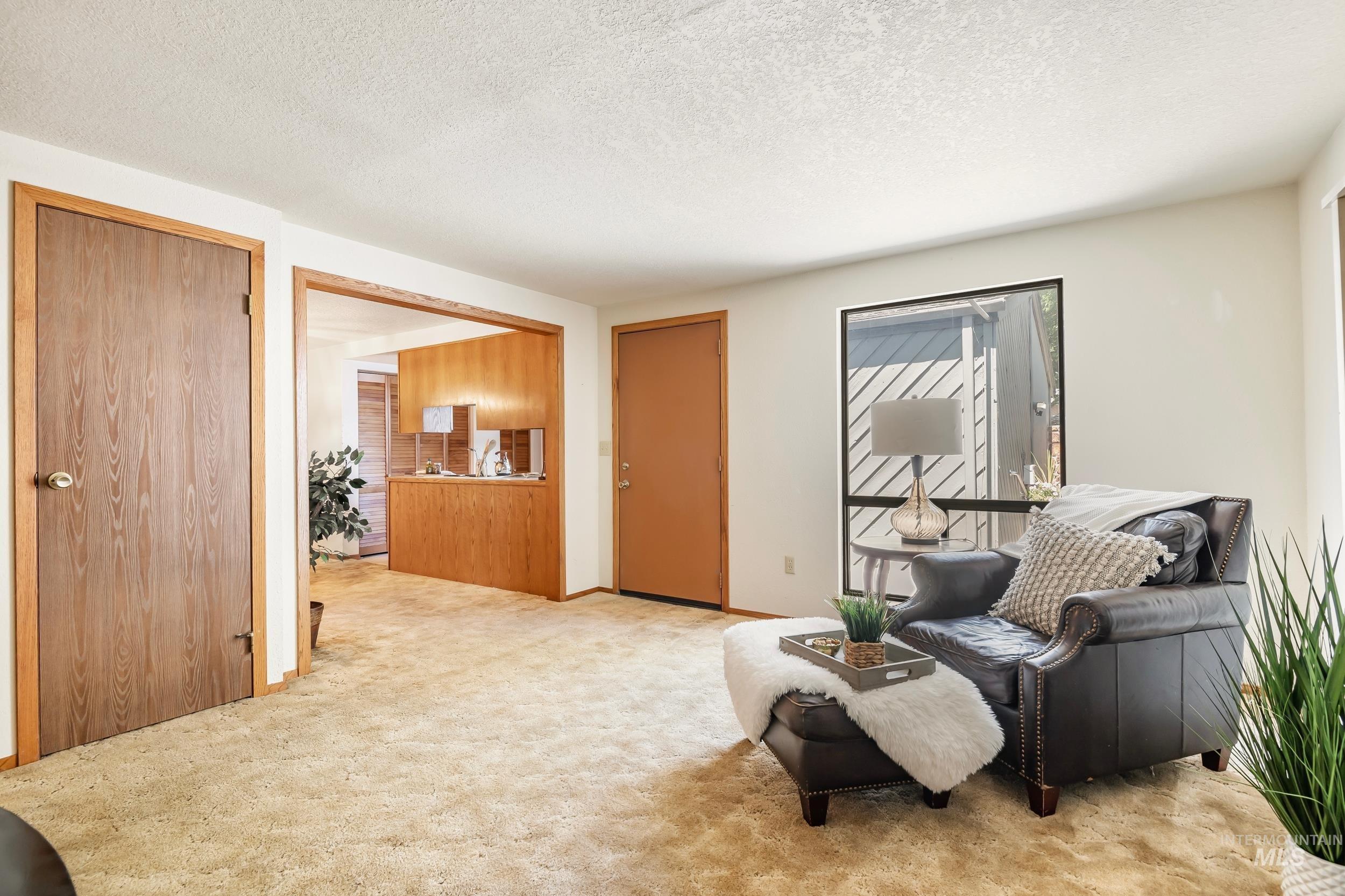 Sitting room featuring light colored carpet and a textured ceiling