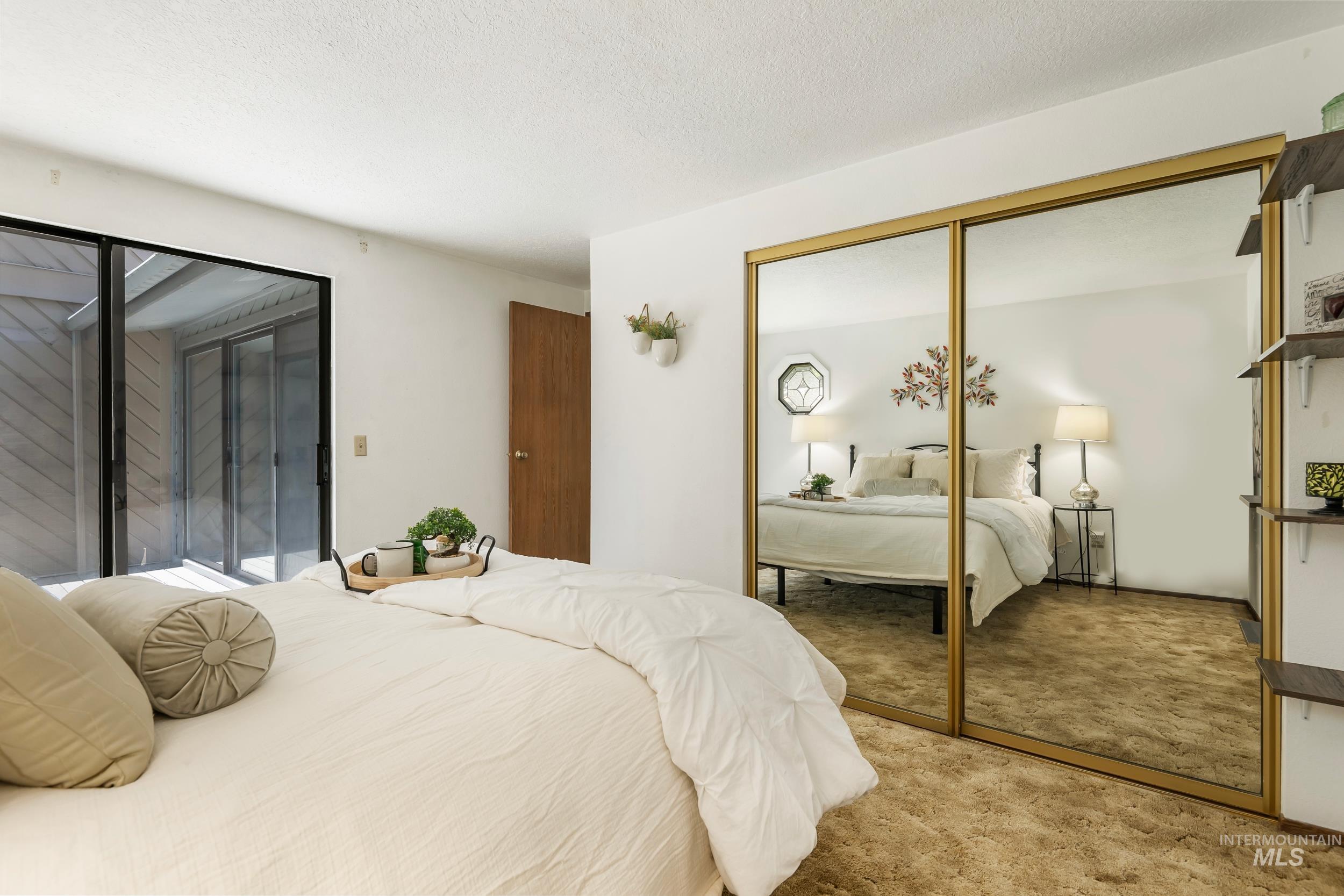 Bedroom featuring light carpet, a closet, a textured ceiling, and access to outside
