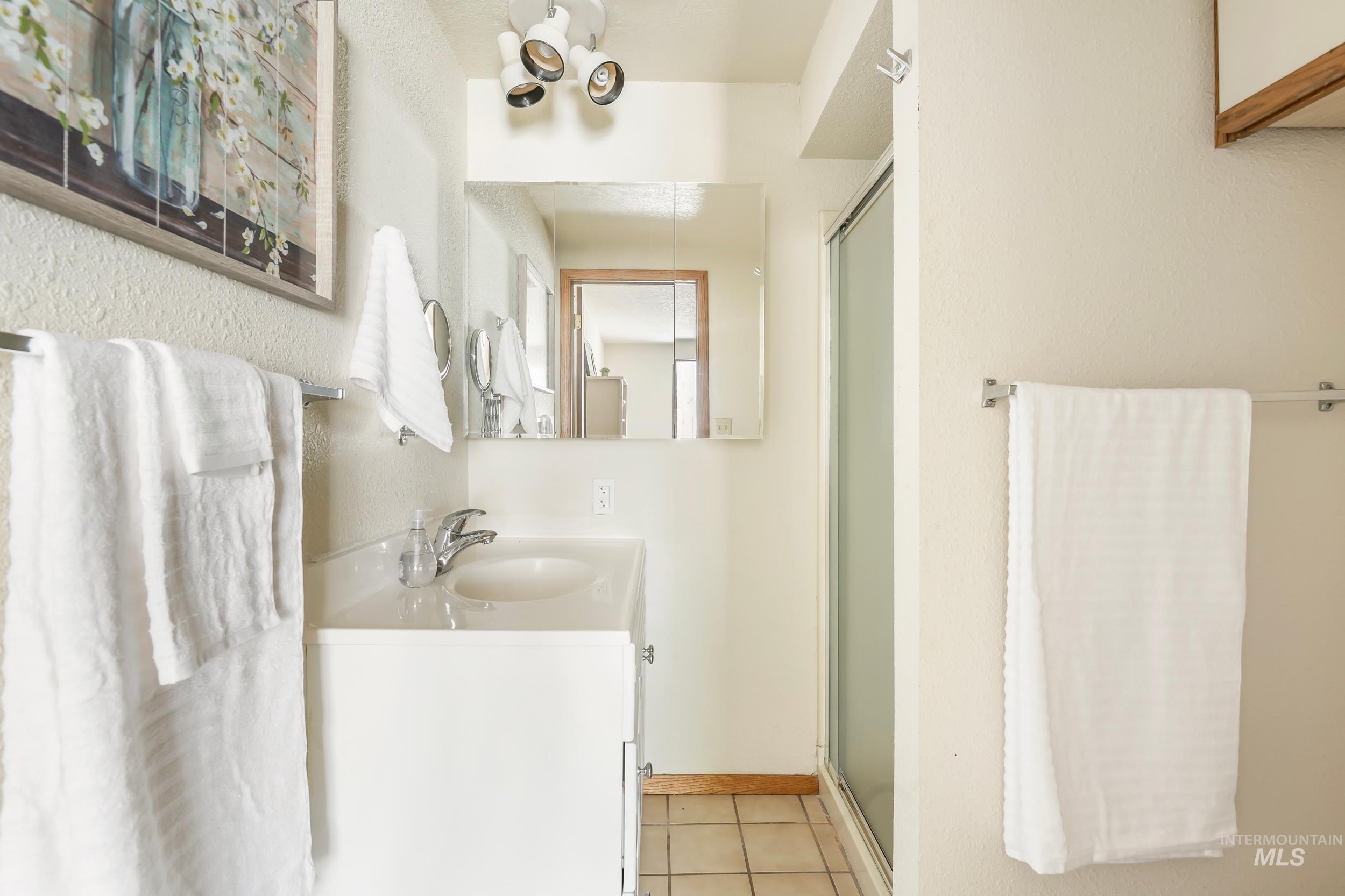 Full bath with tile patterned floors, vanity, and a shower with shower door