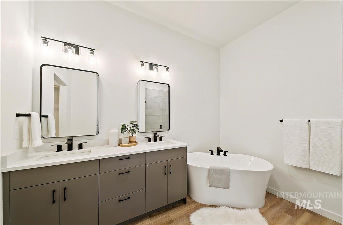 Full bath featuring light wood-type flooring, a freestanding bath, and double vanity