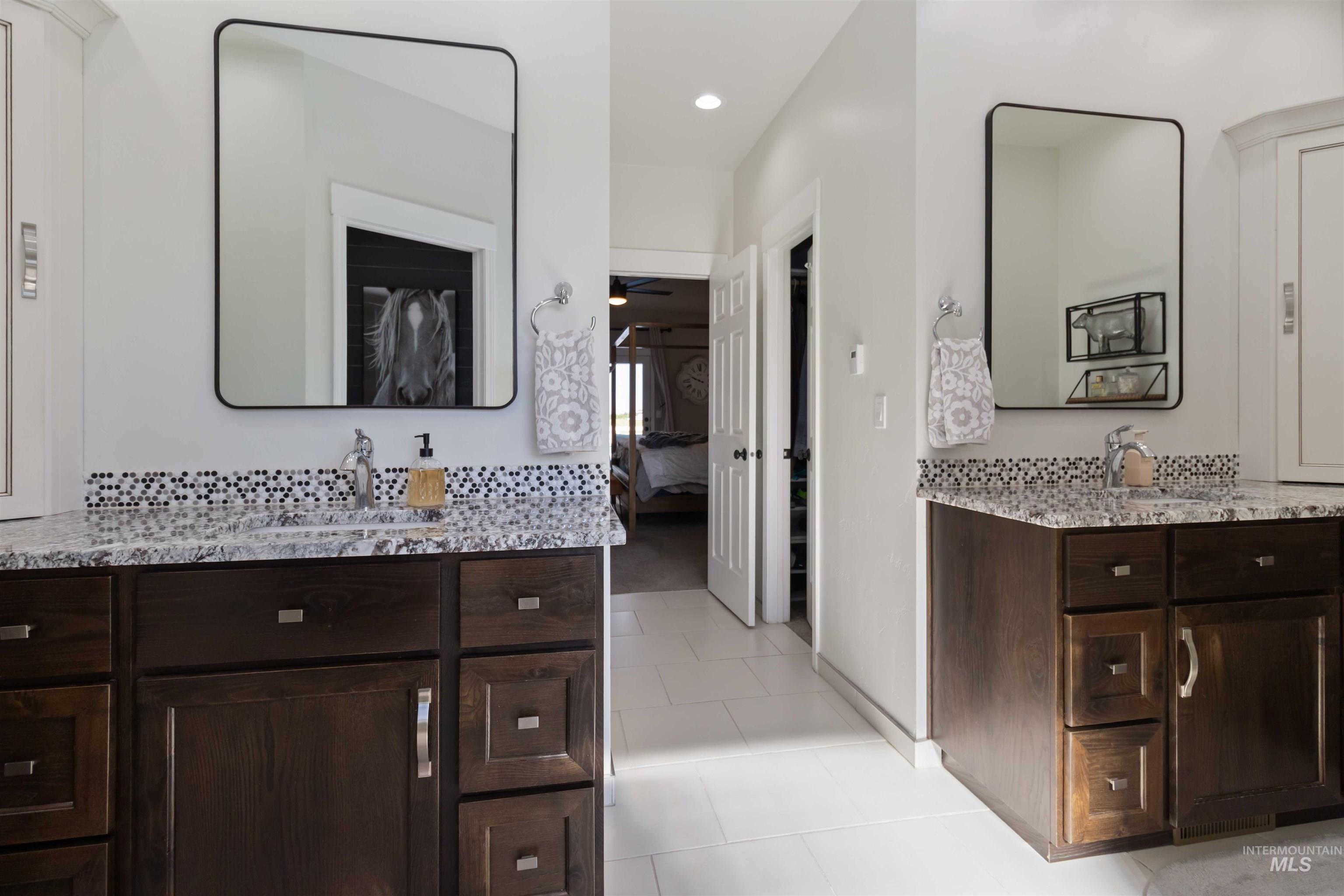 Bathroom featuring two vanities, walk in shower, heated floors , ensuite bathroom, light tile patterned floors, backsplash, and recessed lighting