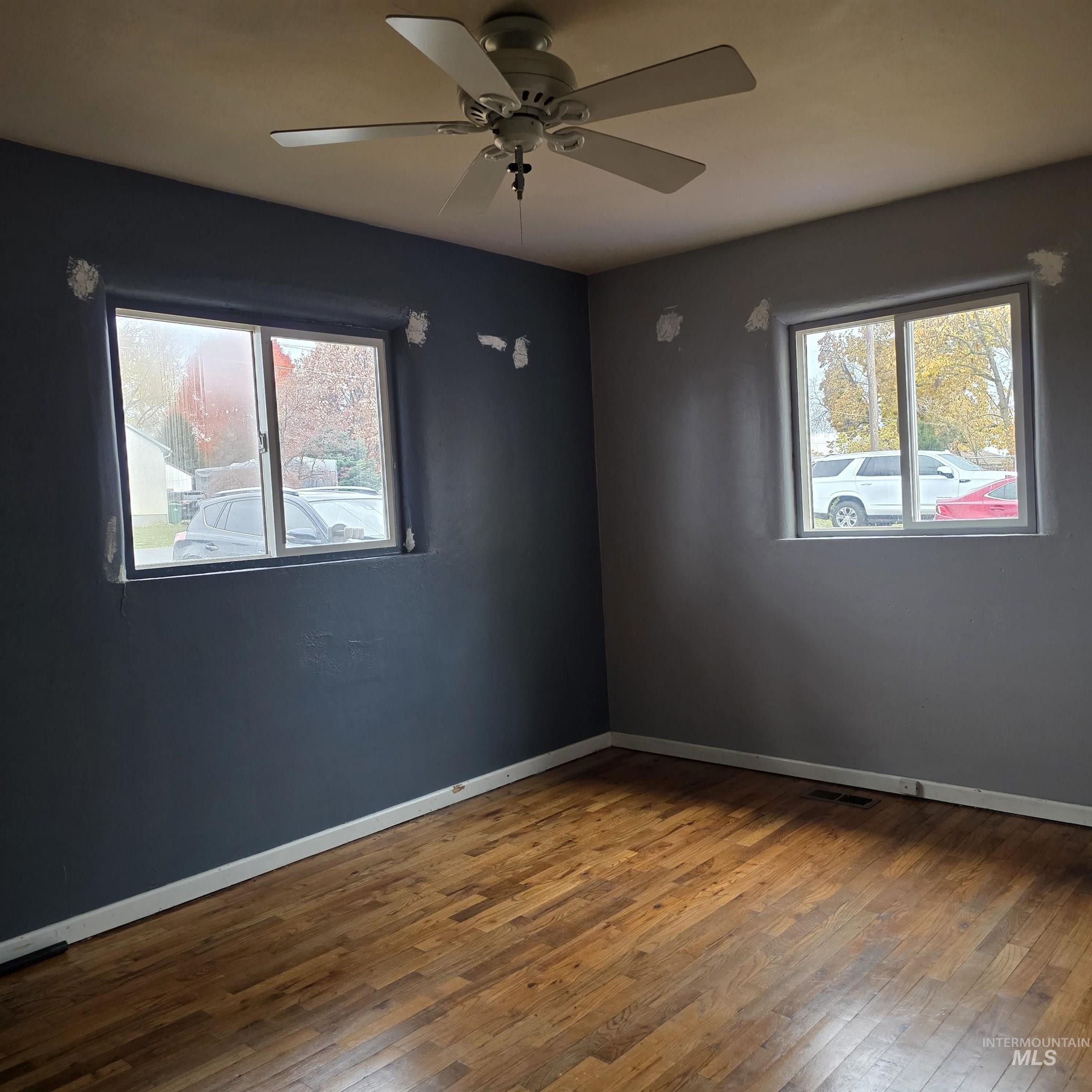 Unfurnished room with hardwood / wood-style floors, healthy amount of natural light, and ceiling fan