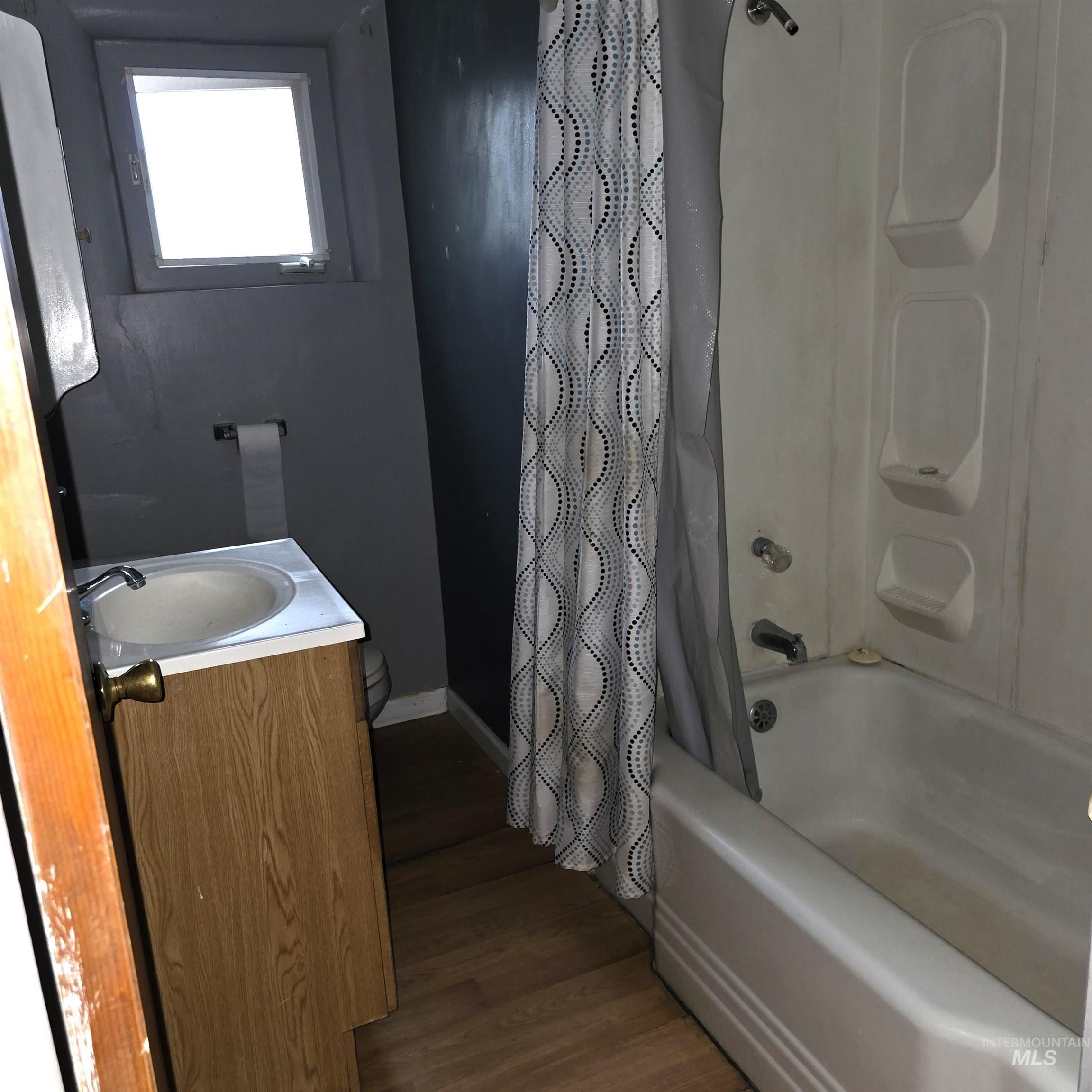 Full bath with vanity, dark wood-style floors, and shower / bath combination with curtain