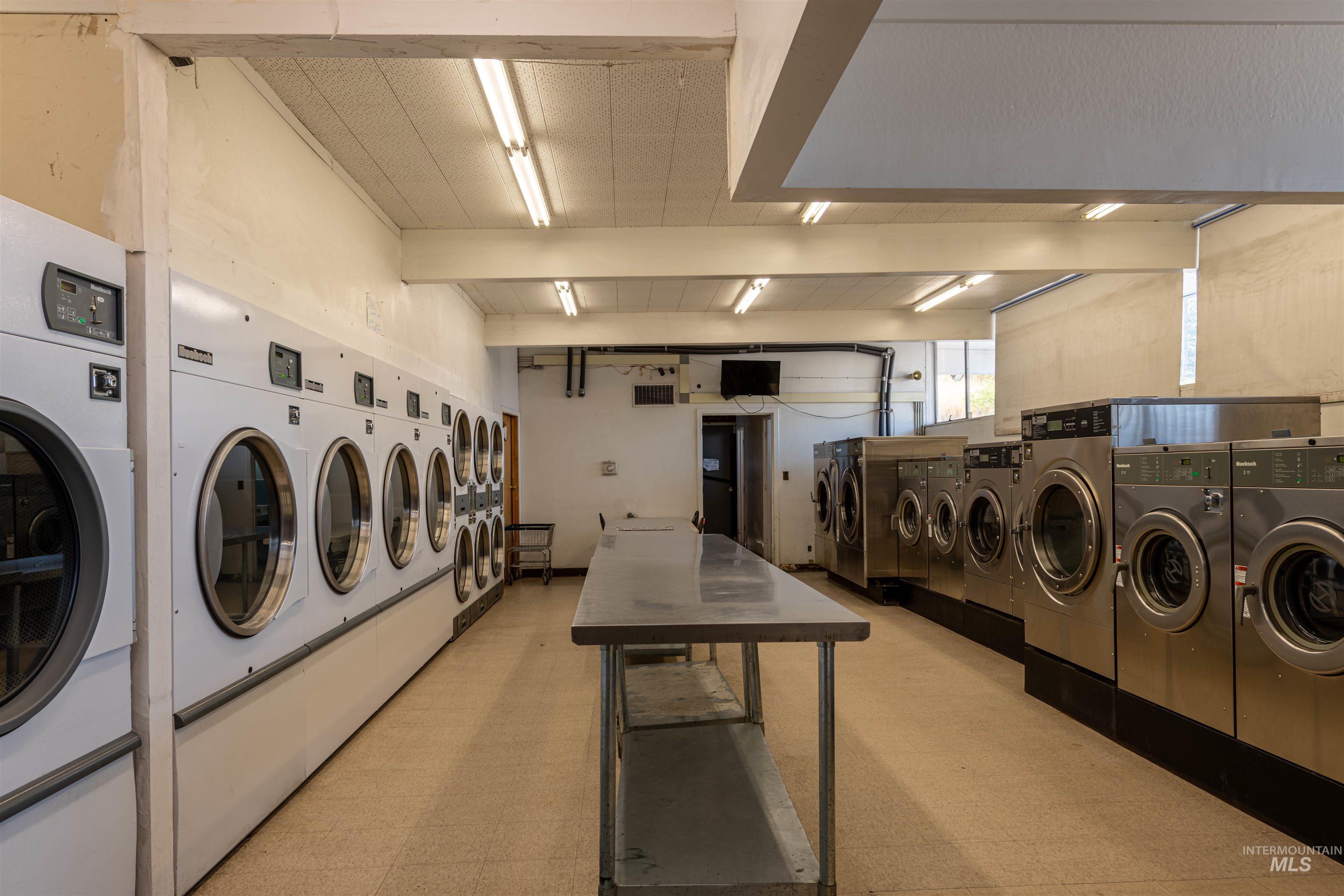 Shared laundry room with washing machine and clothes dryer and beamed ceiling