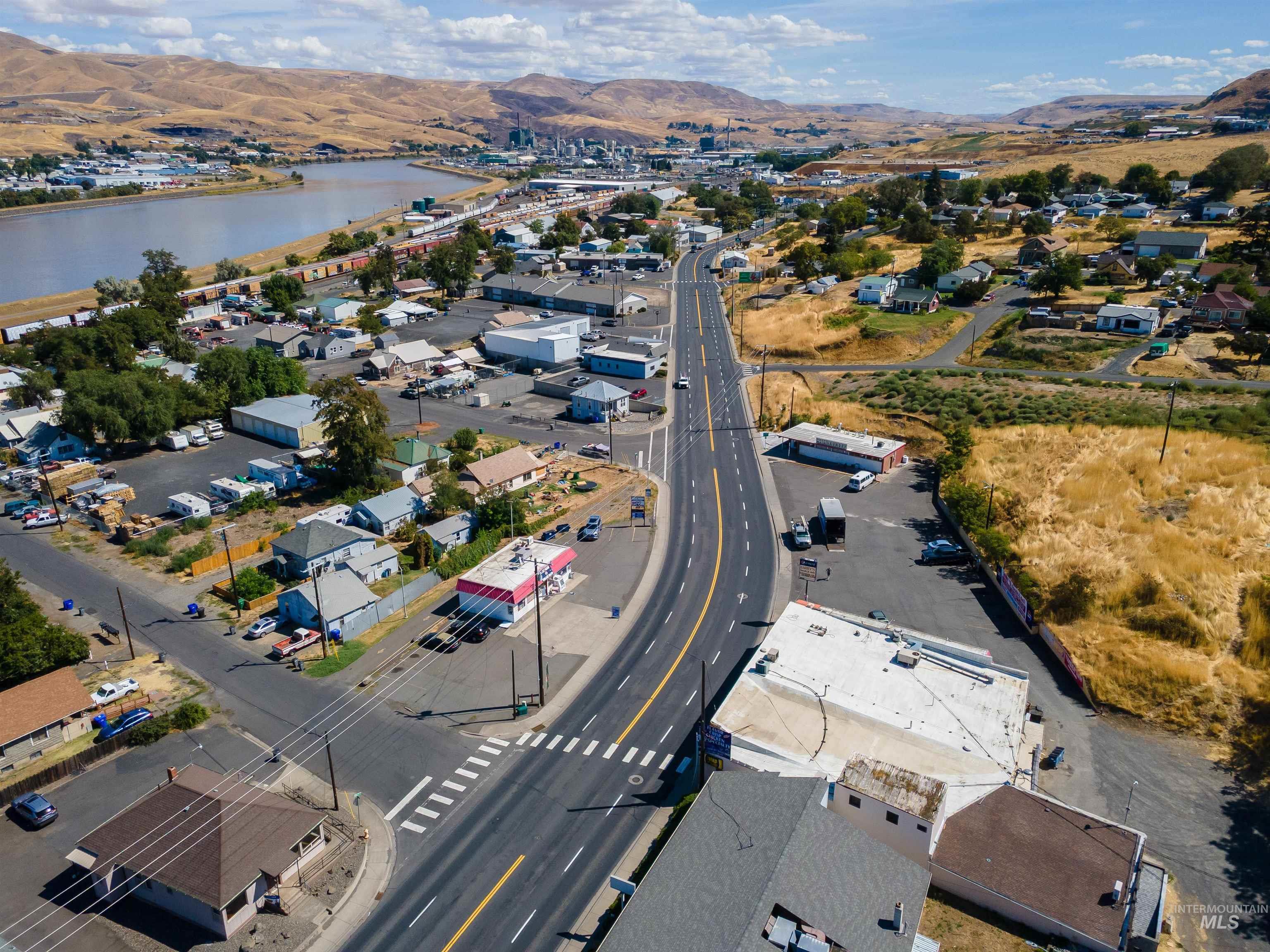 Aerial view of property and surrounding area featuring nearby suburban area and a water and mountain view