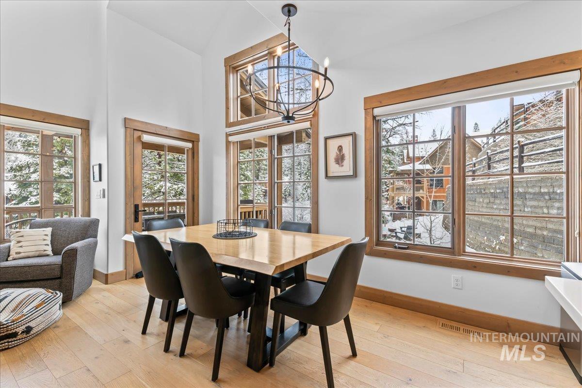 Dining space with light wood-style floors, hanging lights, a high ceiling, and plenty of natural light