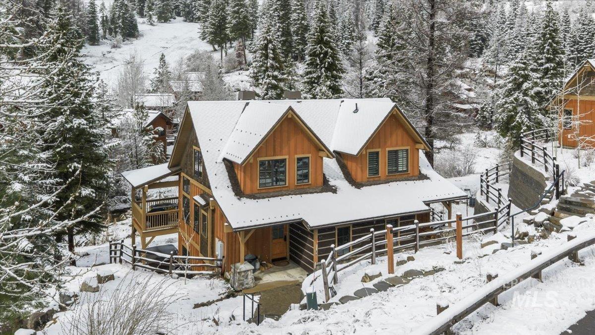 Snow covered rear of property featuring board and batten siding and a deck