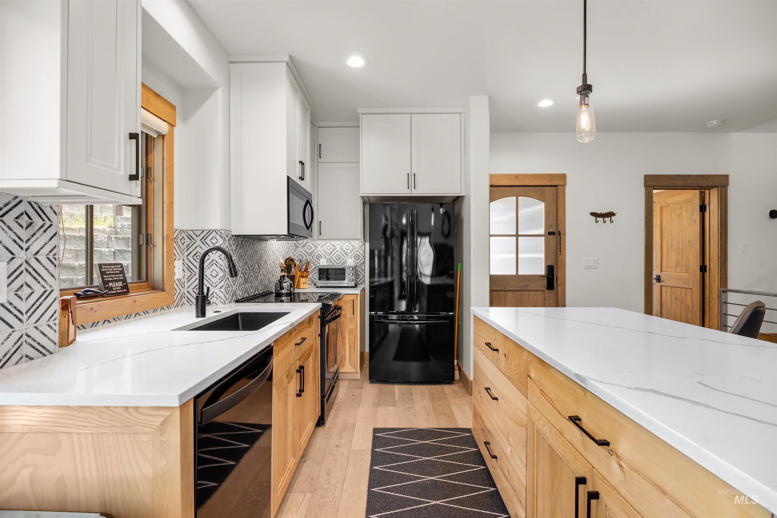 Modern kitchen featuring white upper cabinetry, natural wood-finish lower cabinetry, and light wood-finish flooring