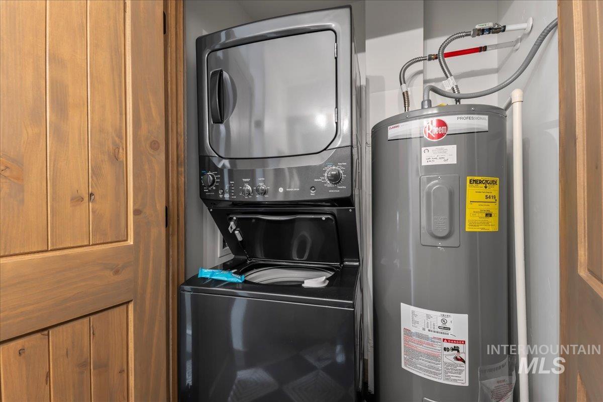 Laundry area featuring water heater and stacked washer and dryer