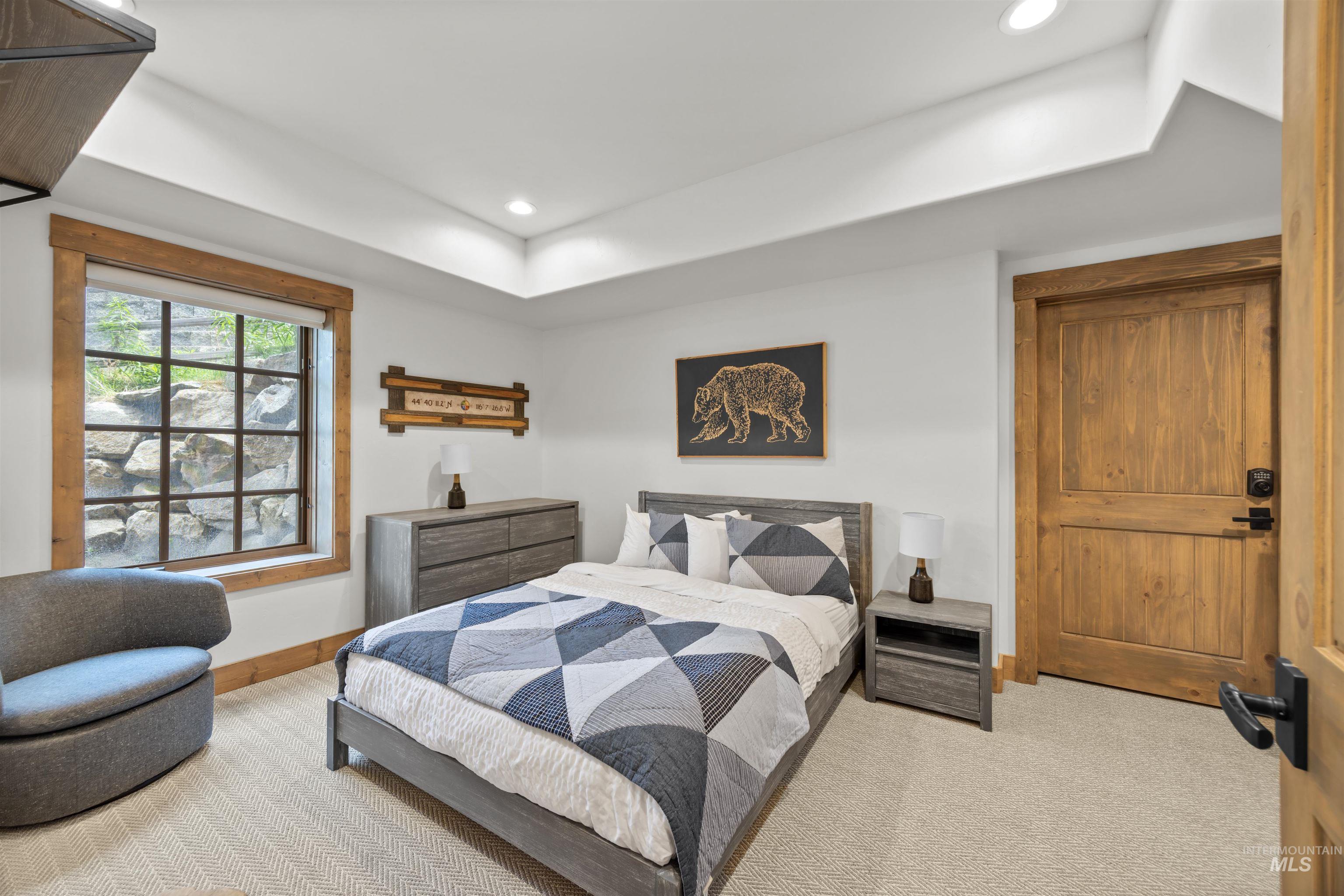 Recessed lighting illuminates a space featuring a wood-trimmed window, a solid wood door with dark hardware, and carpet flooring
