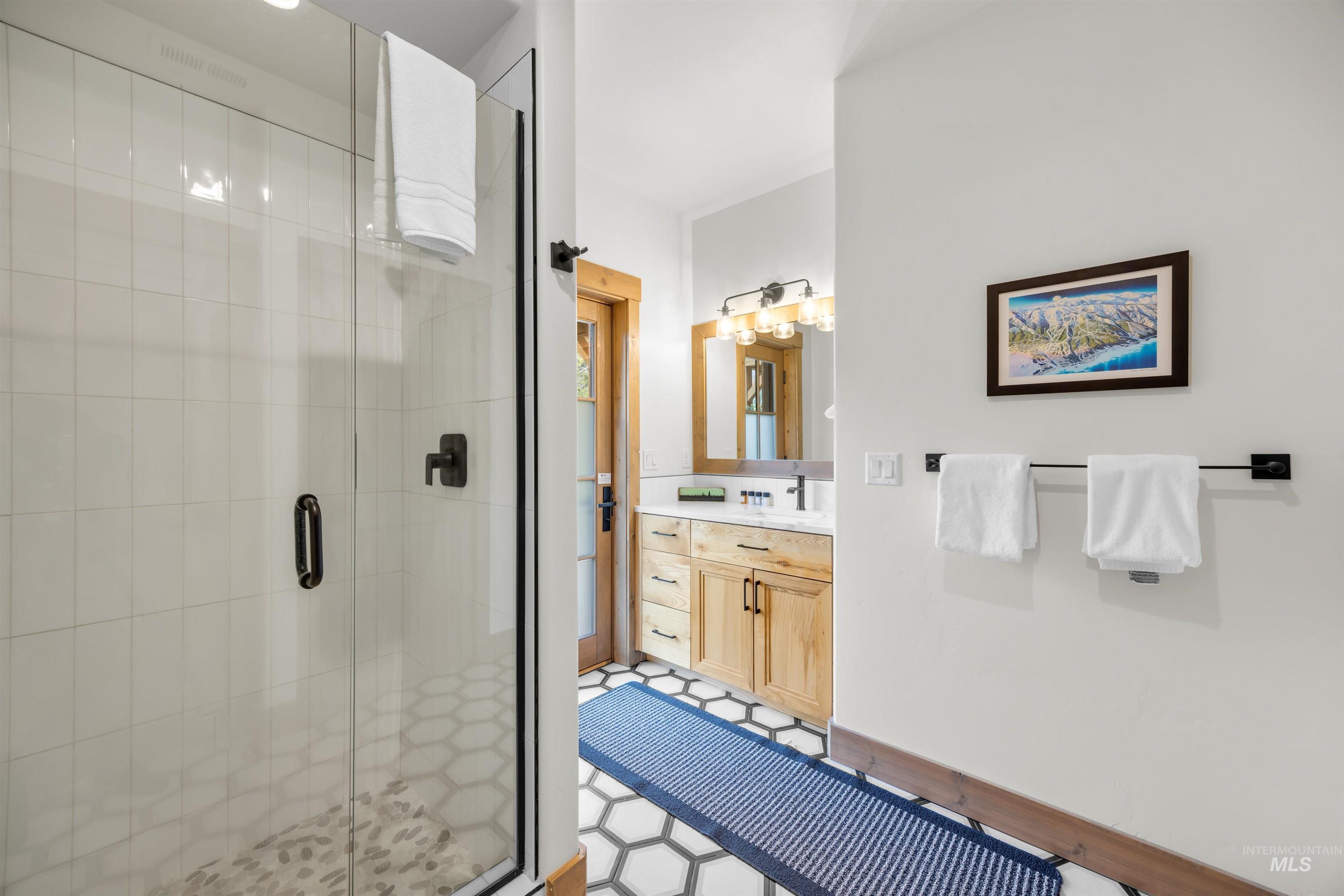 Glass-enclosed shower featuring white subway tile surround and a hexagonal mosaic tile floor