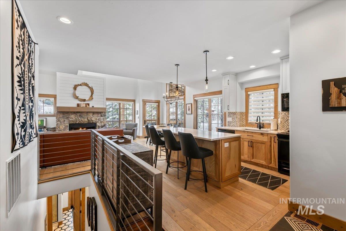 Kitchen with open floor plan, a kitchen island, a fireplace, light wood-style flooring, and tasteful backsplash