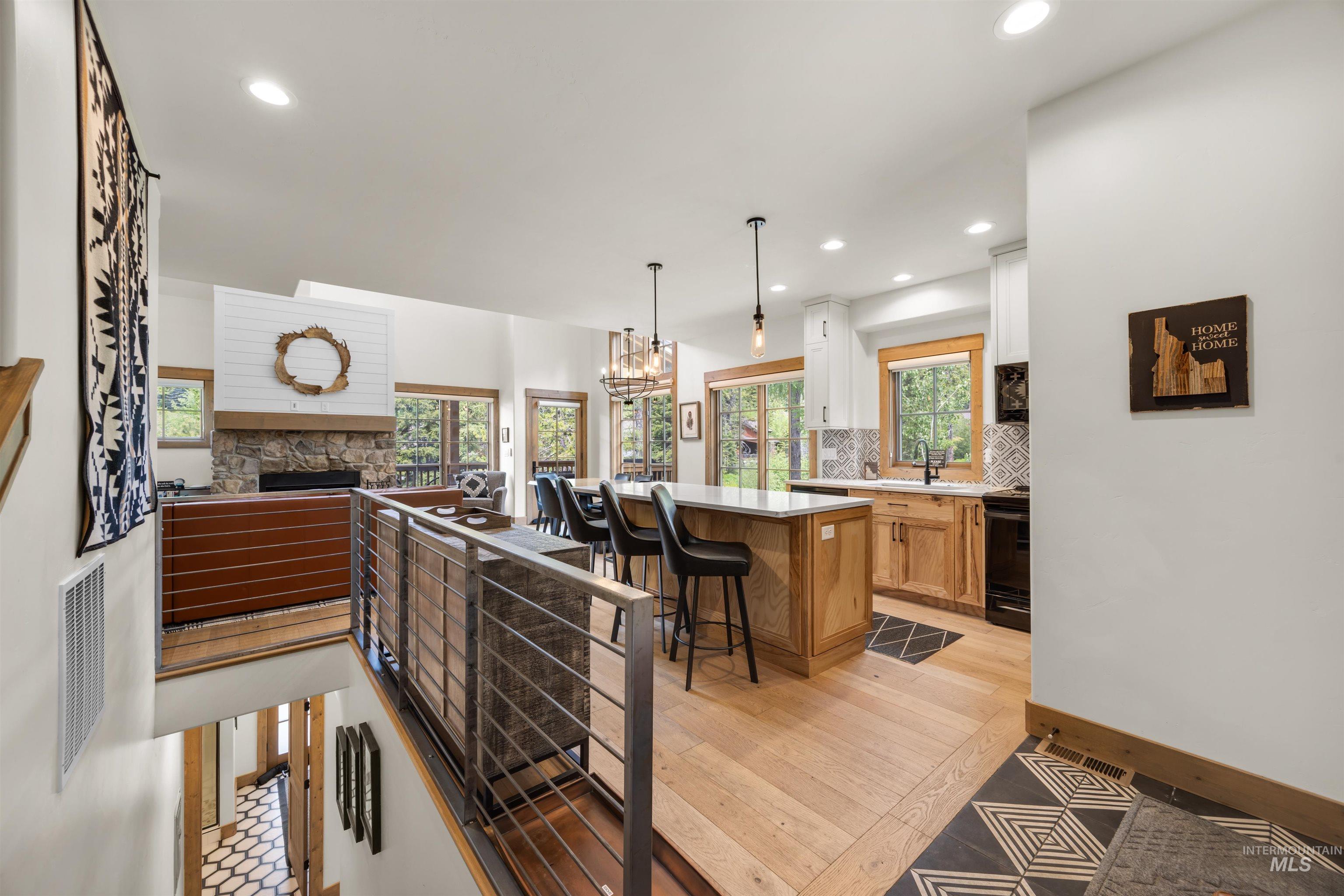 Open-concept living space featuring wood-finish flooring, a stone fireplace with a shiplap accent, and a kitchen island with seating