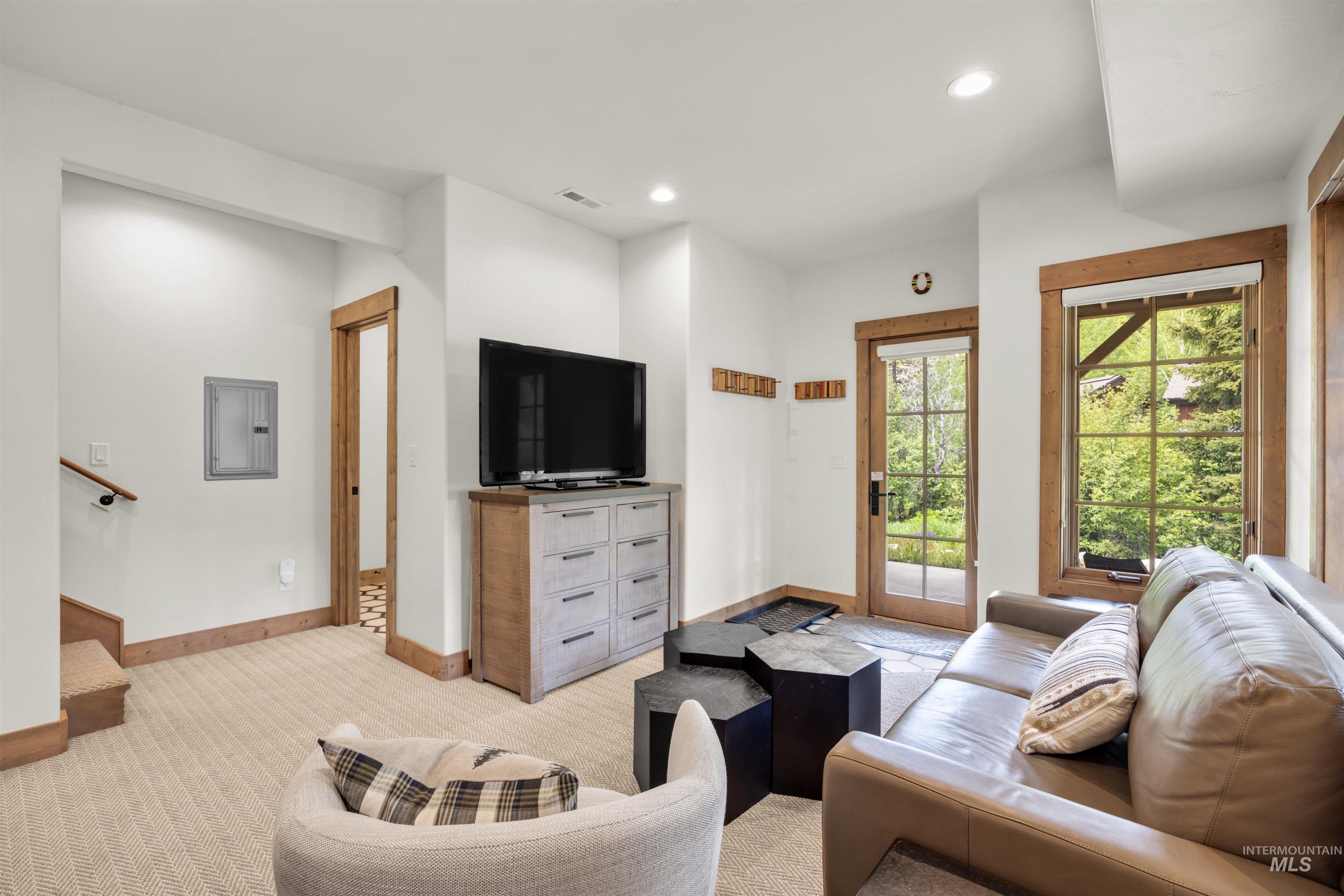 Living area featuring a glass-paned door, a large window with natural wood trim, recessed lighting, and neutral-toned carpeting